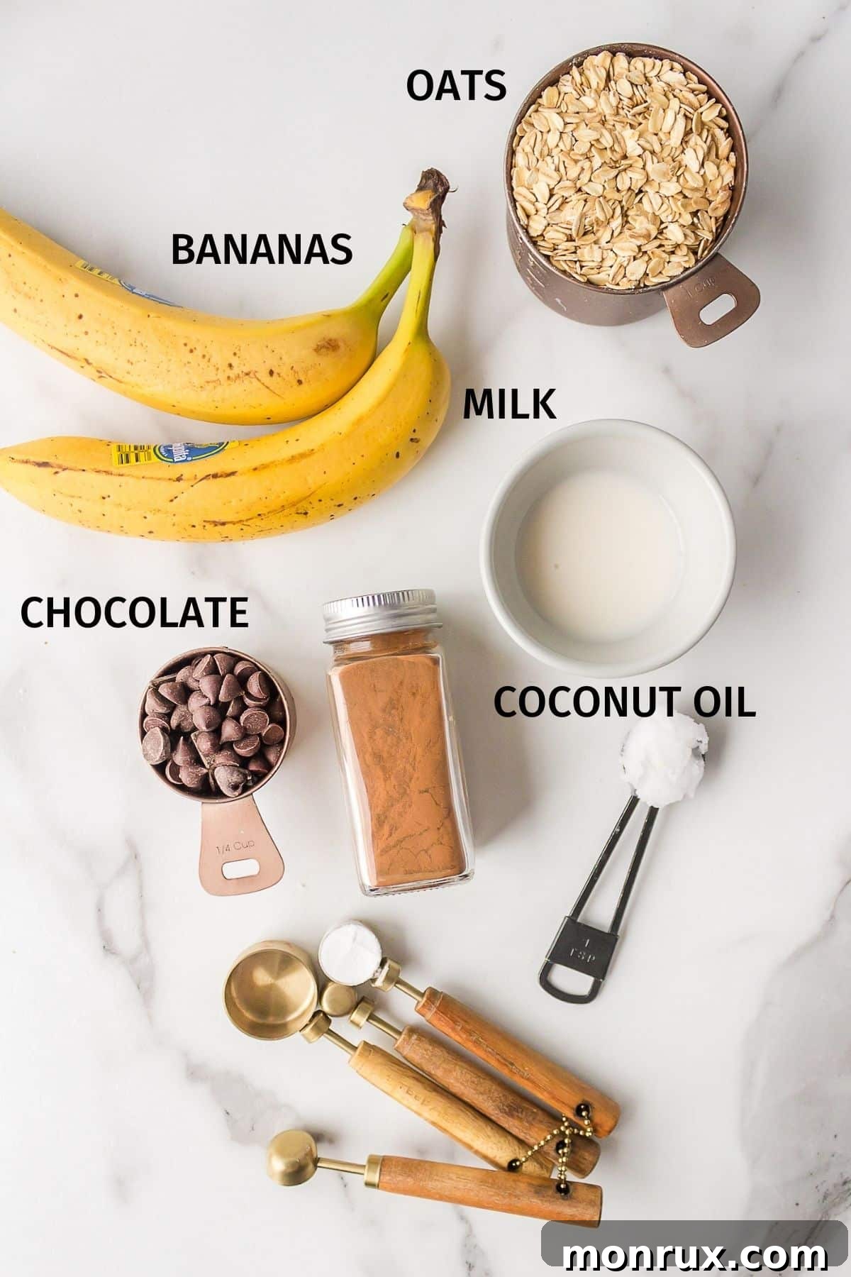 Clearly labeled ingredients for healthy banana oatmeal cookies arranged on a pristine white backdrop, ready for preparation.