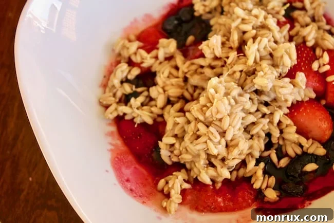 A close-up of a delightful bowl of freshly prepared sprouted oat groat cereal, generously topped with a colorful assortment of mixed berries, showcasing its wholesome appeal.