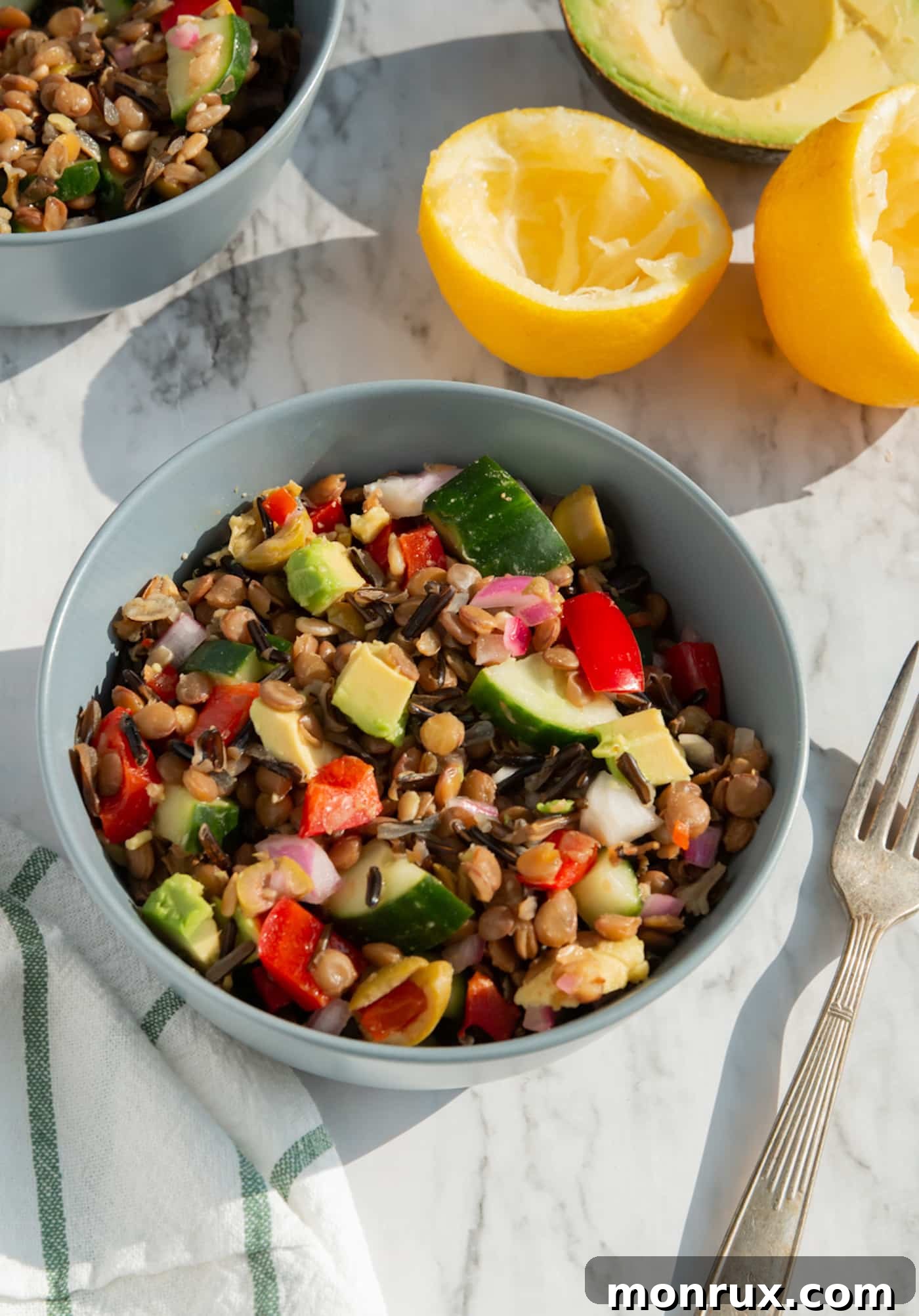 A vibrant Wild Rice Lentil Salad with chopped vegetables in a bowl, placed on a rustic tabletop.