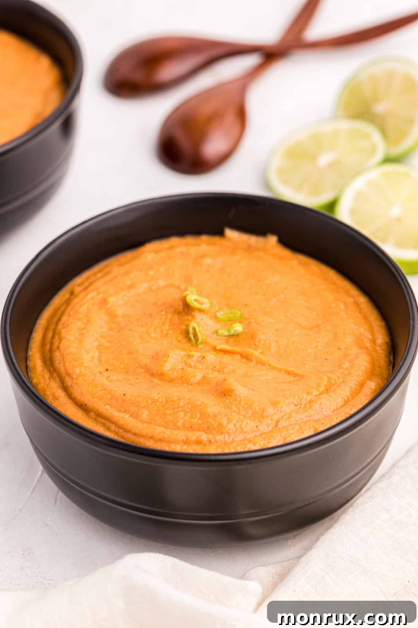 A bowl of creamy, rich peanut butter soup with fresh herbs and a hint of spice, served elegantly in a black bowl, ready to be enjoyed.