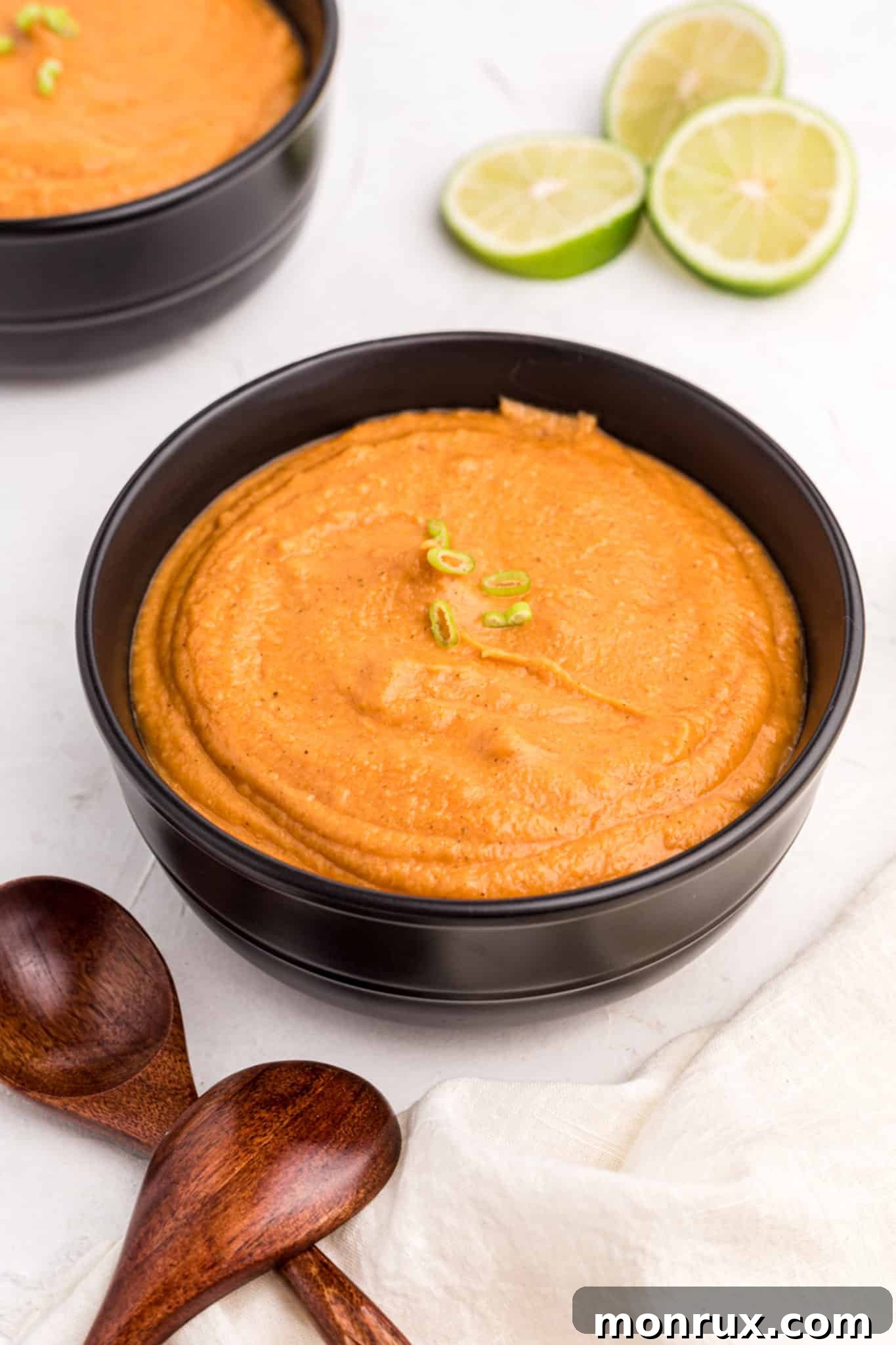 A close-up of the finished peanut butter soup, garnished with a fresh lime wedge and a sprinkle of cilantro, highlighting its creamy texture and inviting aroma.