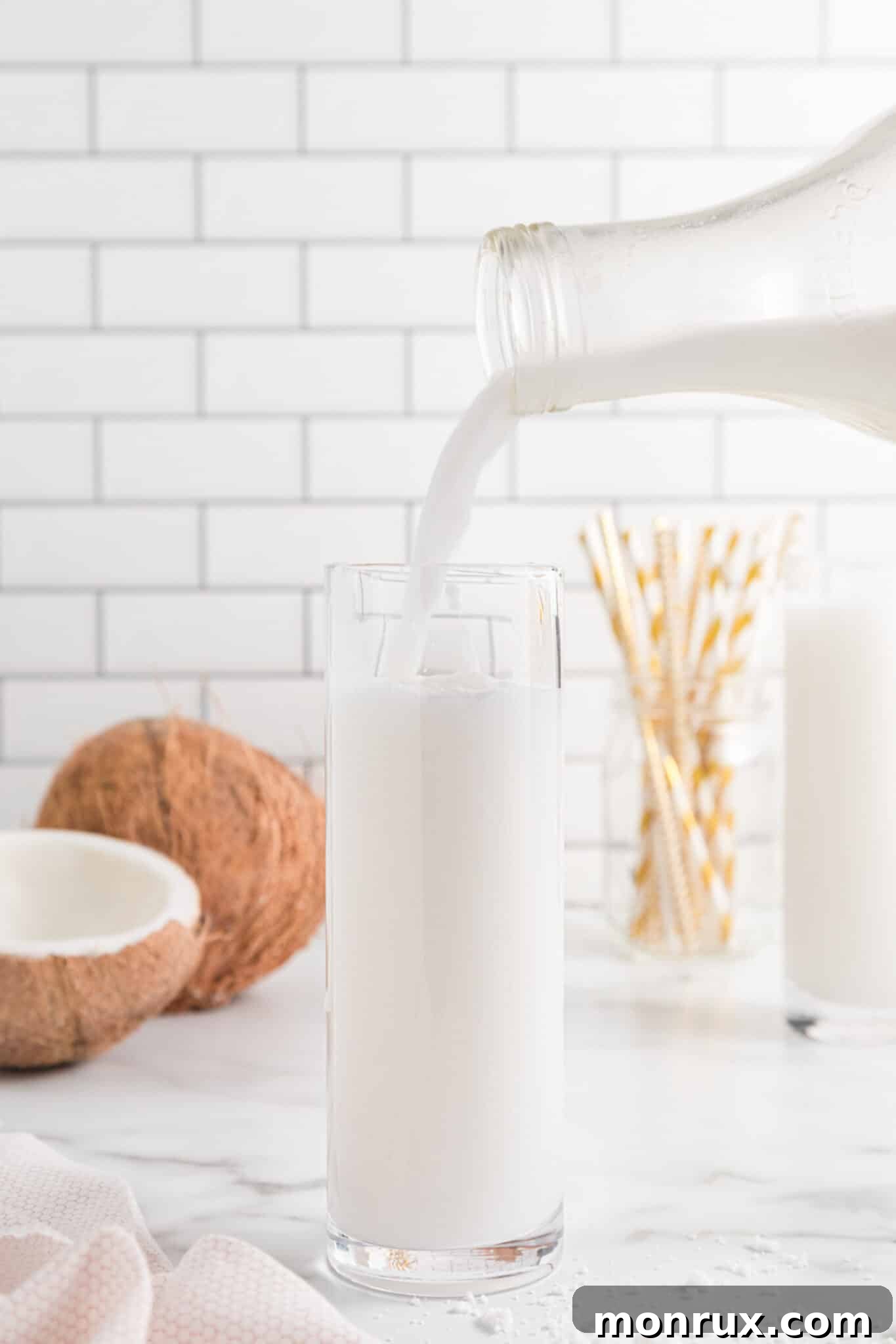 Pouring homemade Vitamix coconut milk into a glass jar for storage.