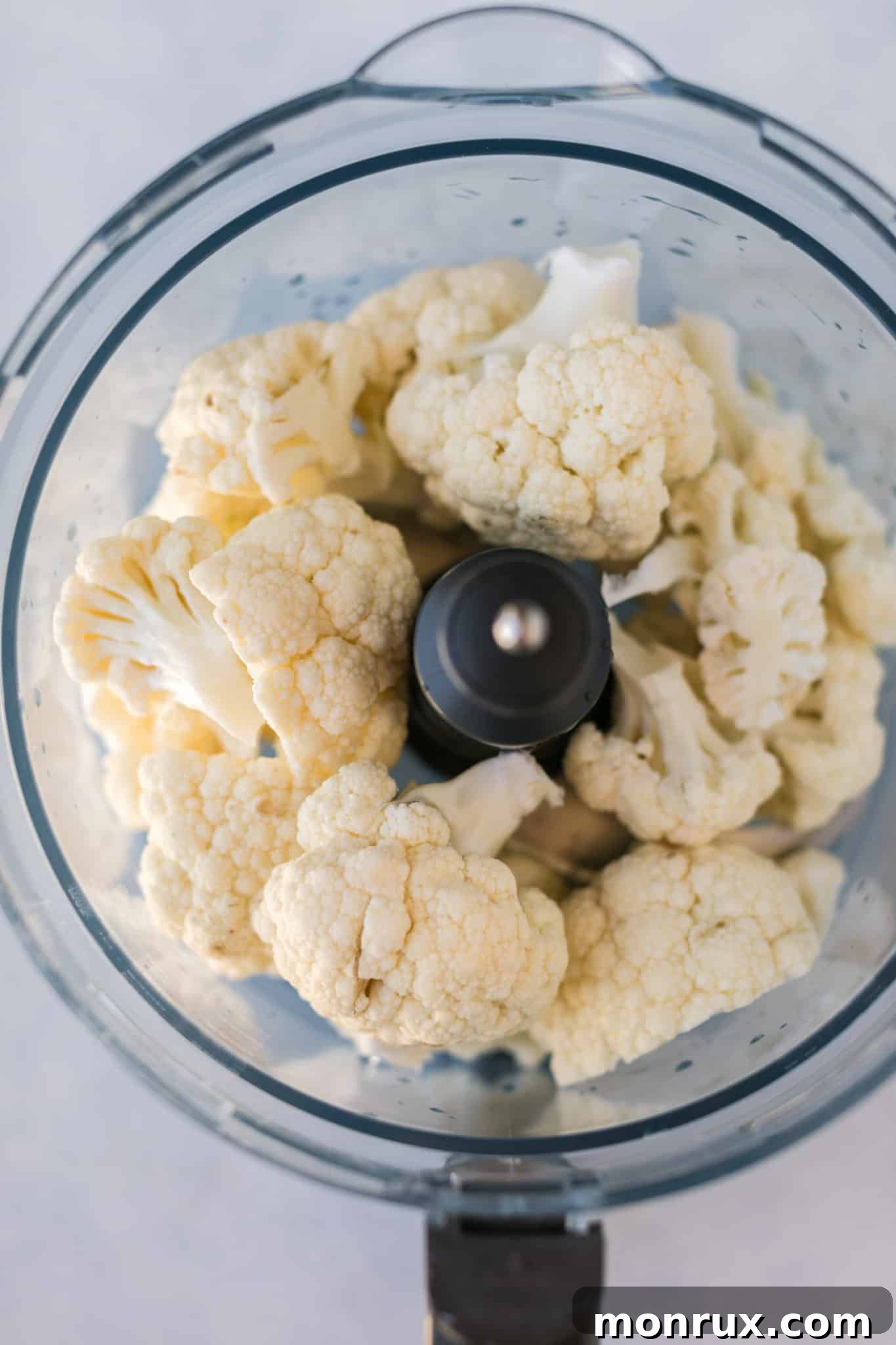 Cauliflower florets being processed in a food processor to create cauliflower rice, the base for the oatmeal.