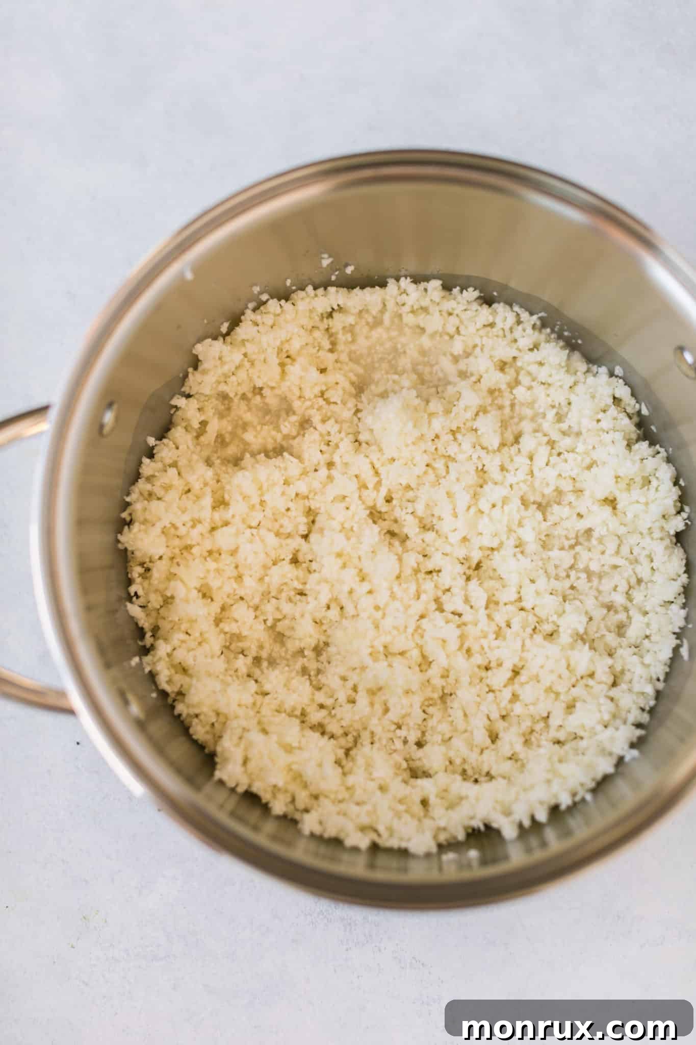 Cauliflower rice simmering in a pot with almond milk, ready to be transformed into a creamy breakfast.