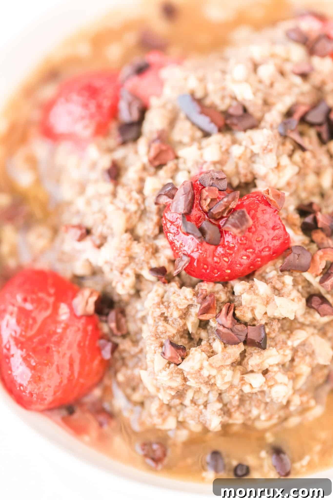 Close-up texture of cooked chocolate cauliflower oatmeal with fresh strawberries and cacao nibs, showing its inviting and hearty consistency.