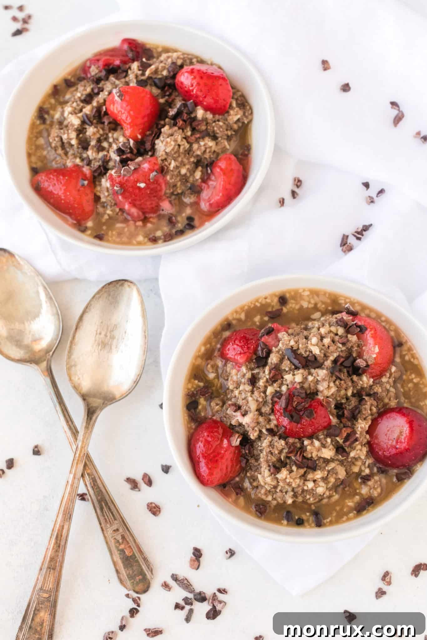 Two bowls of chocolate cauliflower oatmeal generously topped with fresh strawberries and cacao nibs, ready to be enjoyed.