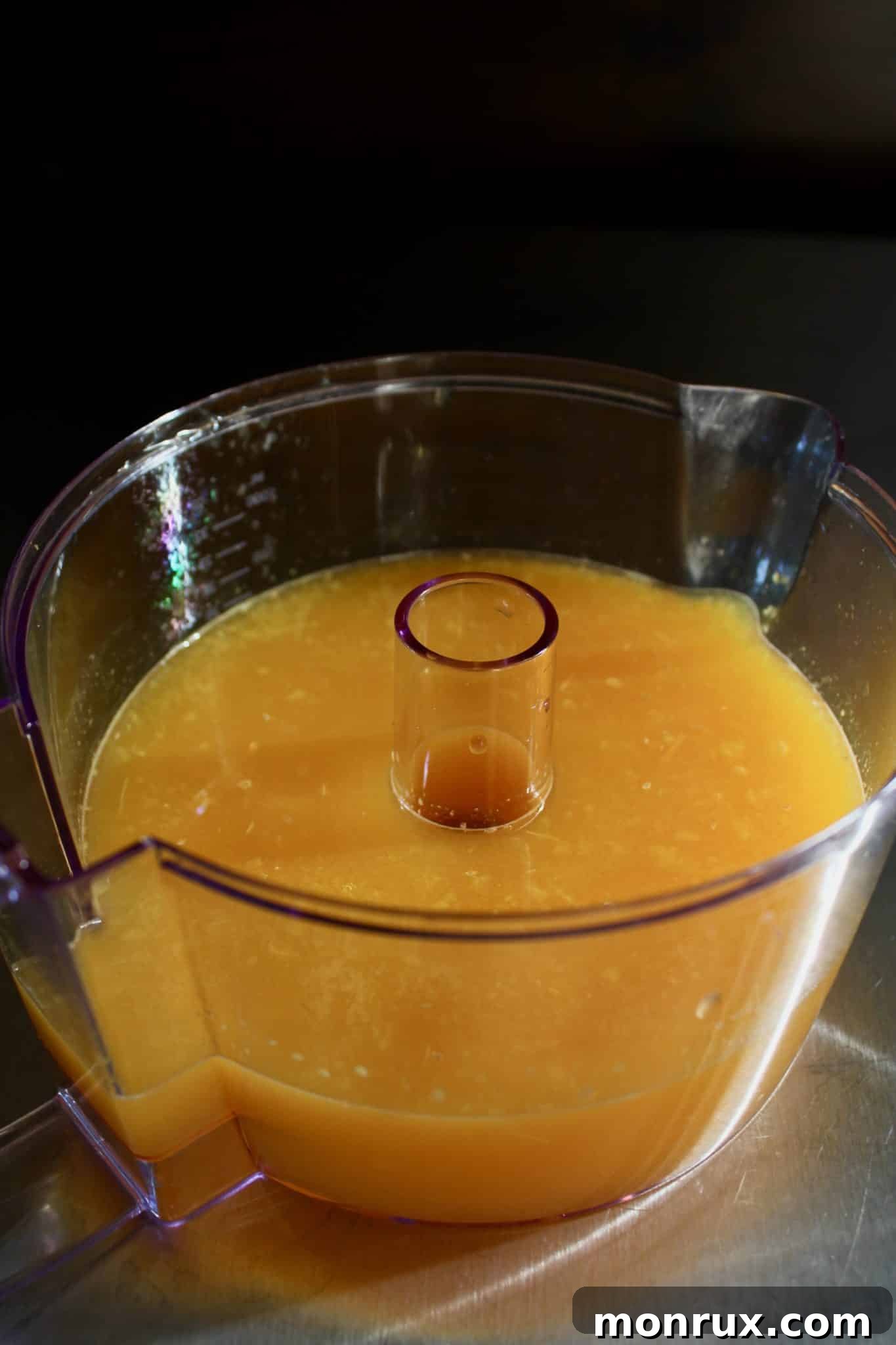 Freshly squeezed orange juice being poured into a container, highlighting the natural ingredients.