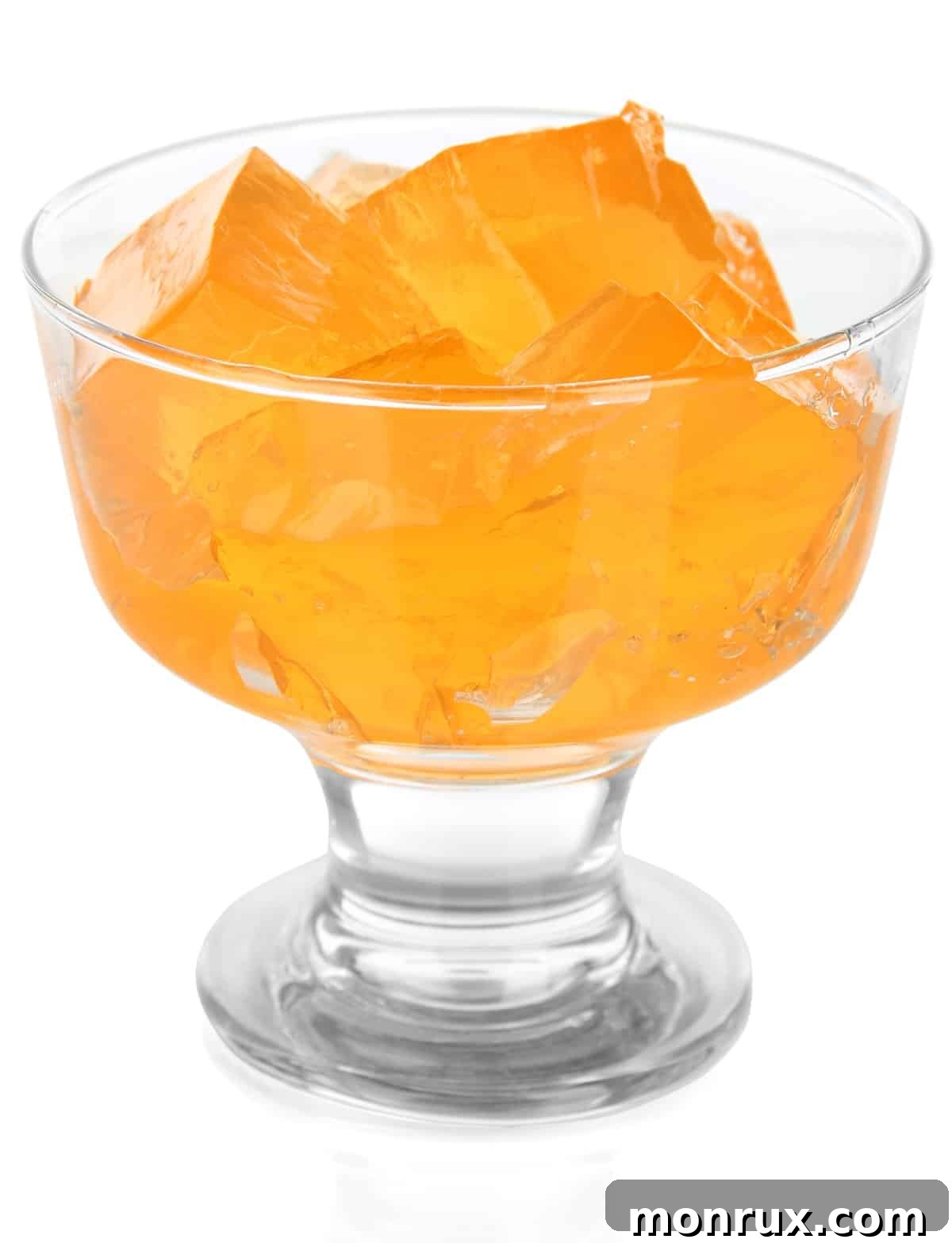 Orange jello cut into perfect cubes and served in a elegant parfait glass, showcasing its delightful texture.