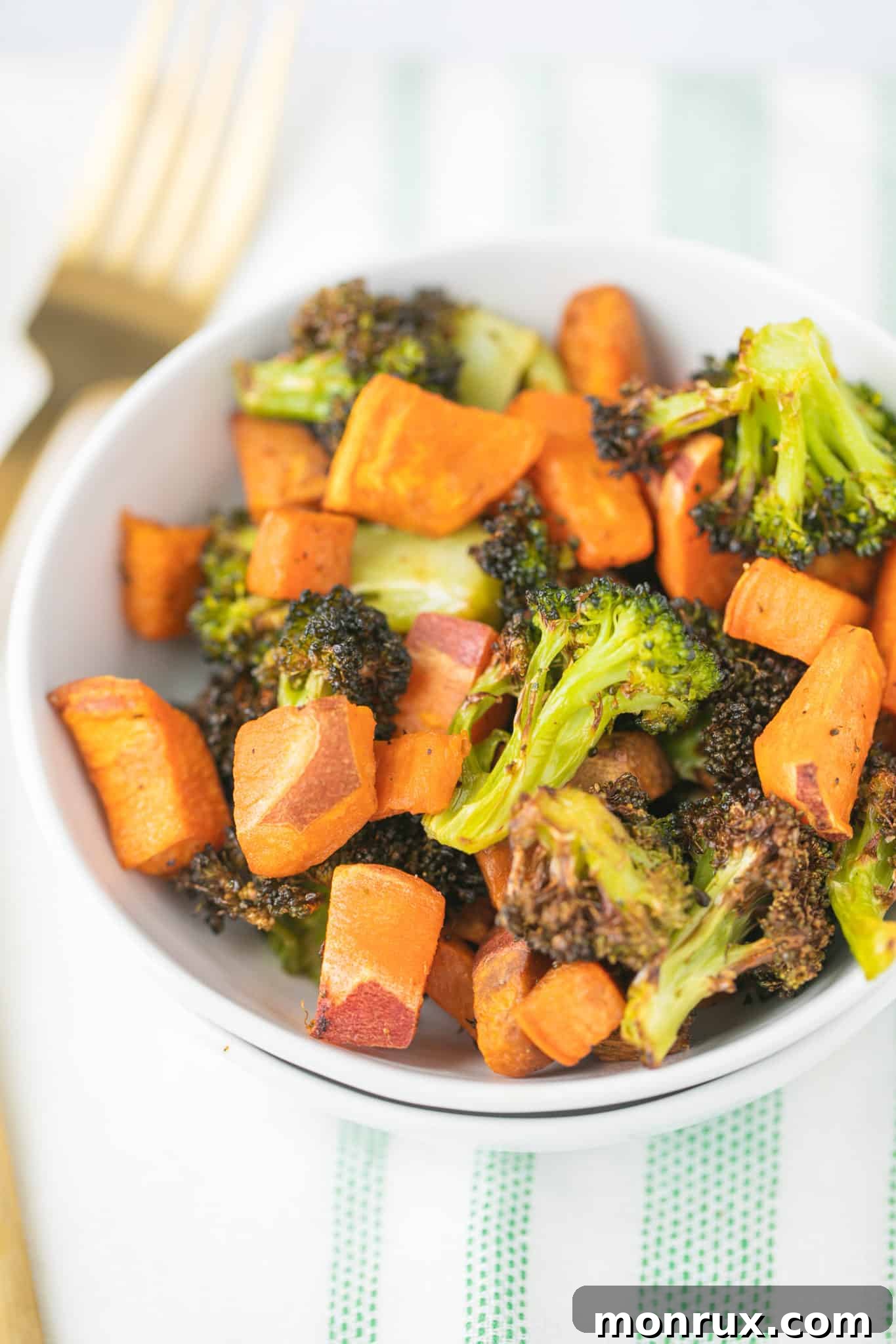 Roasted broccoli and sweet potato in a white bowl with a fork