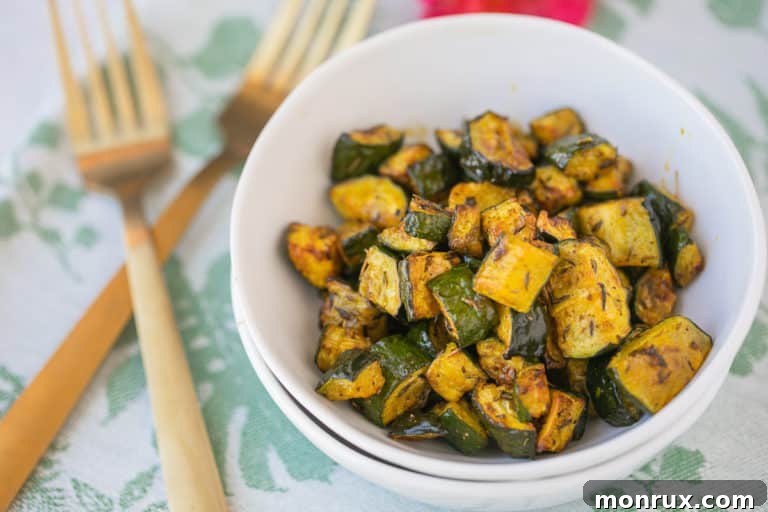 bowl of roasted zucchini with two gold forks