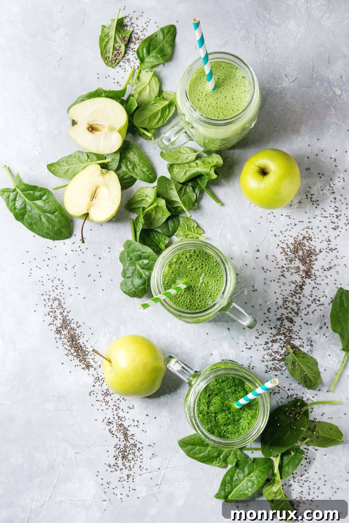 green smoothie on a table with apple and spinach.