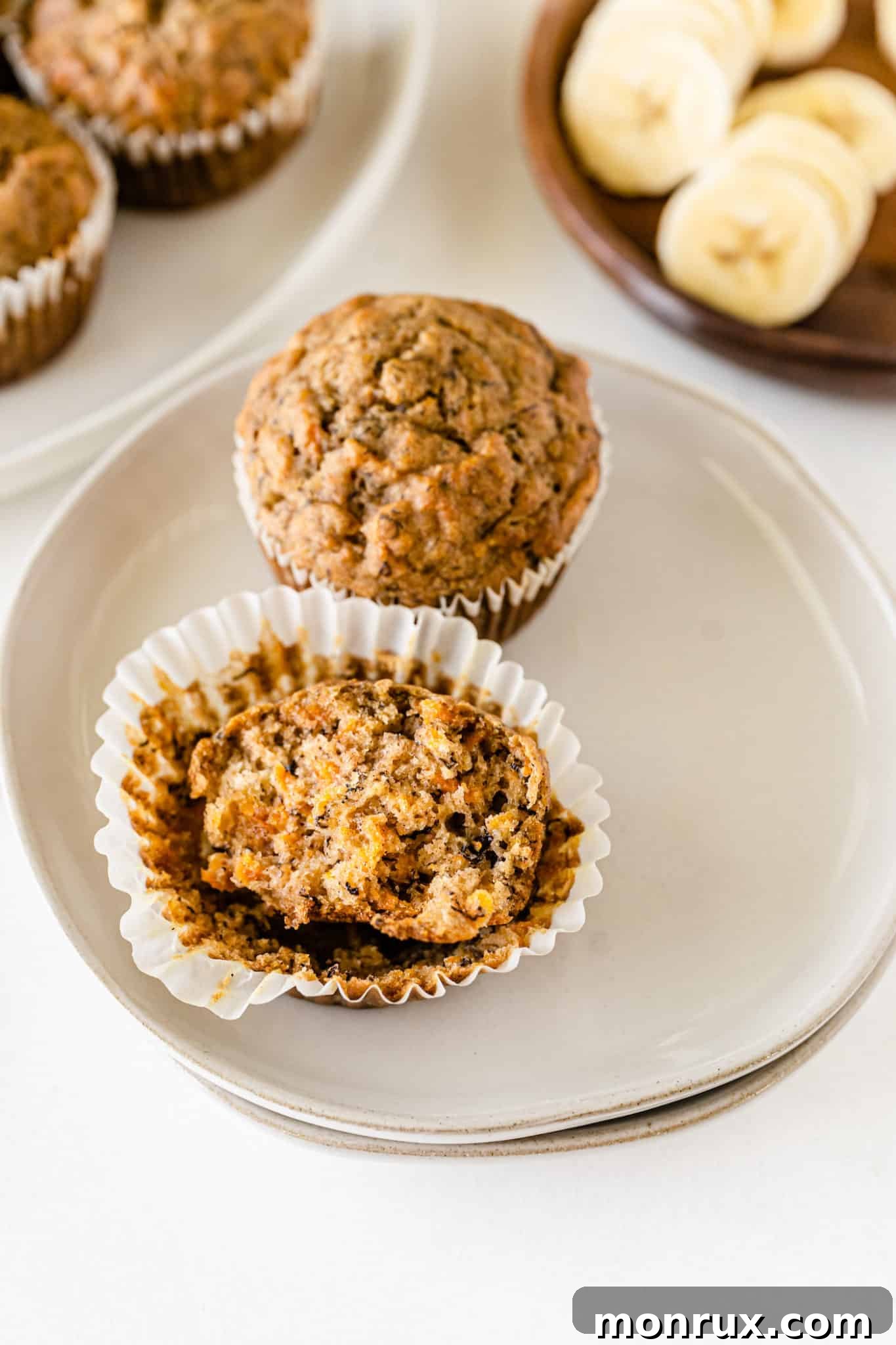 A single banana carrot muffin served on a small plate with a fork, ready to be enjoyed.