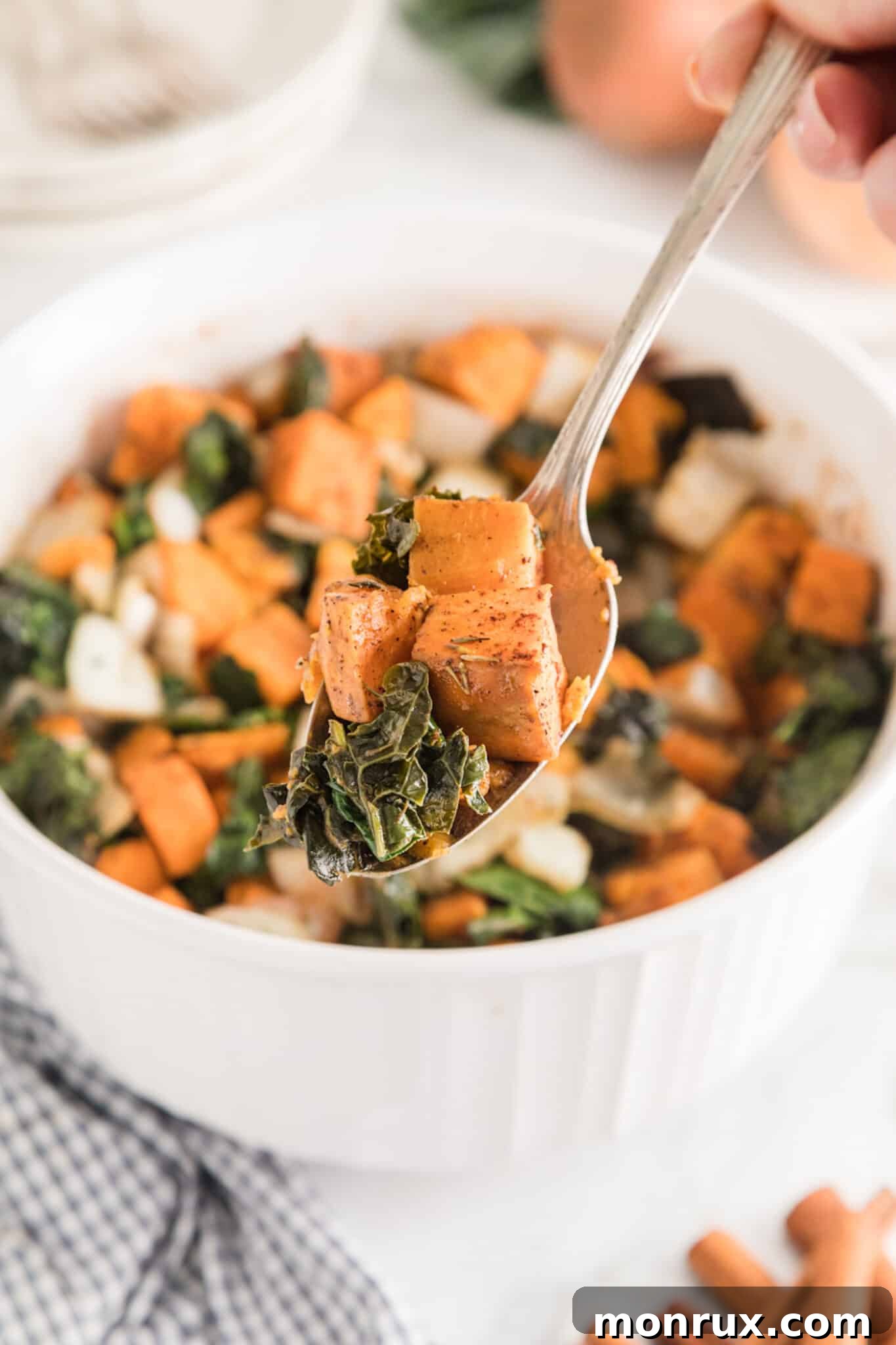 A forkful of sweet potato and kale over the serving bowl.
