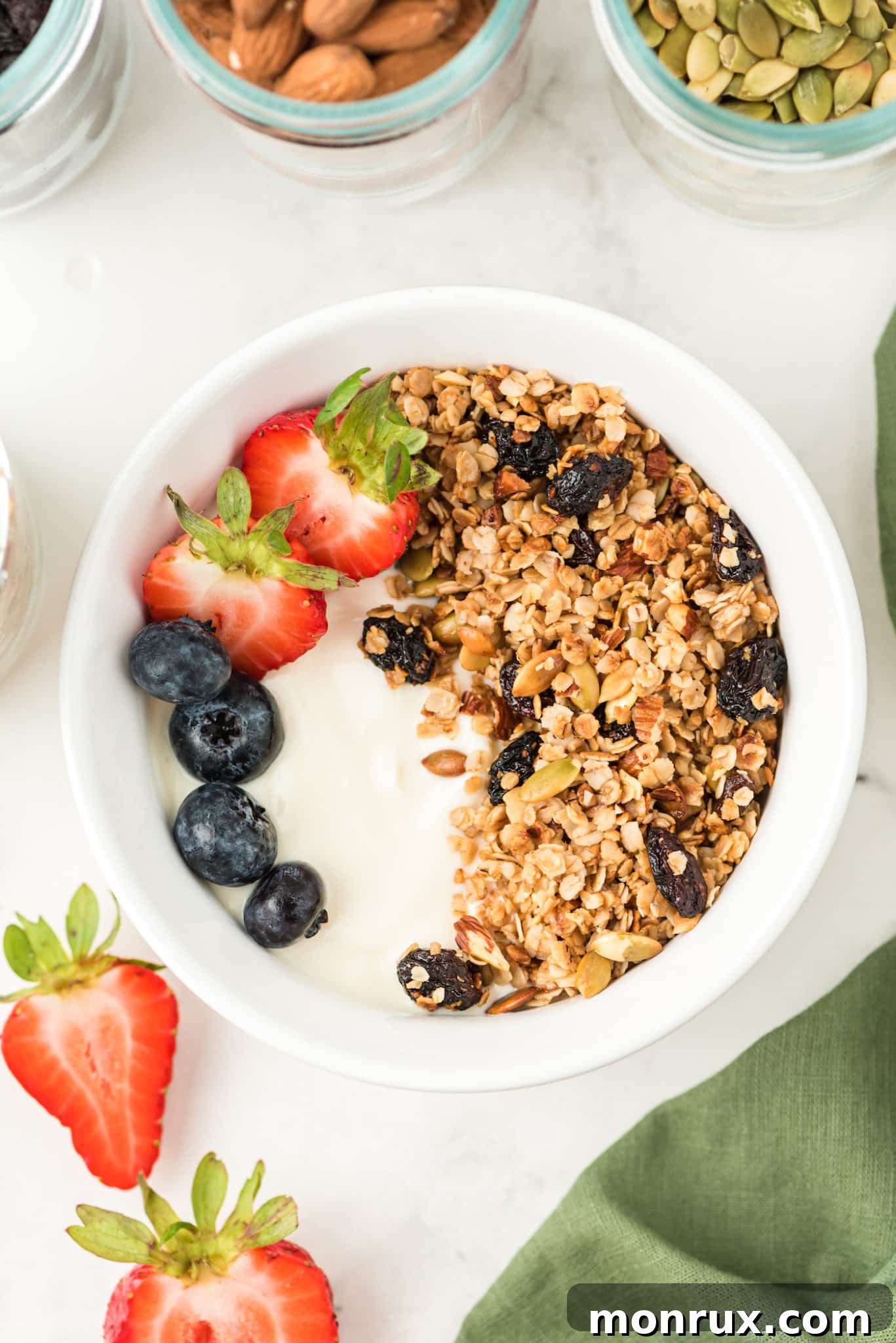 A vibrant bowl of creamy yogurt topped with golden air fryer granola and an assortment of fresh berries and sliced fruit.