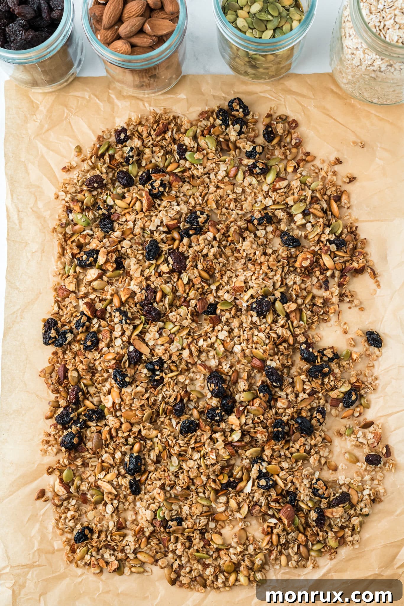 A close-up shot of golden-brown air fryer granola, freshly baked and spread out on parchment paper to cool.