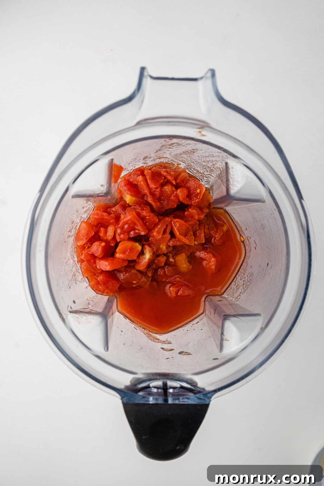 Diced tomatoes being added into a Vitamix blender jar.