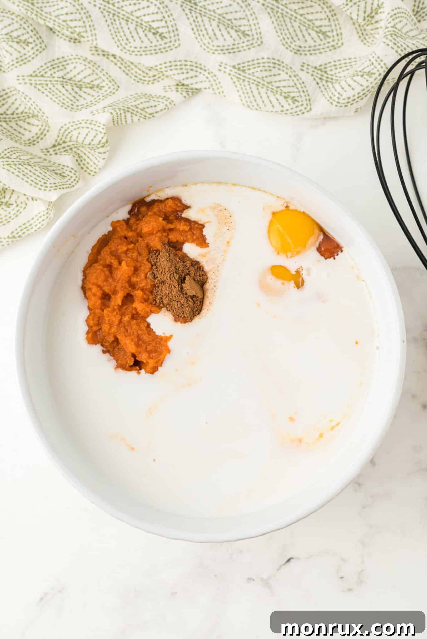 Coconut milk being poured into the mixing bowl with other dairy-free pumpkin pudding ingredients.