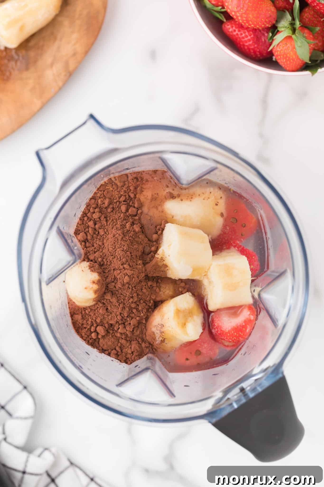 Ingredients being added to a high-speed blender for a chocolate banana smoothie, illustrating the first step of the recipe.