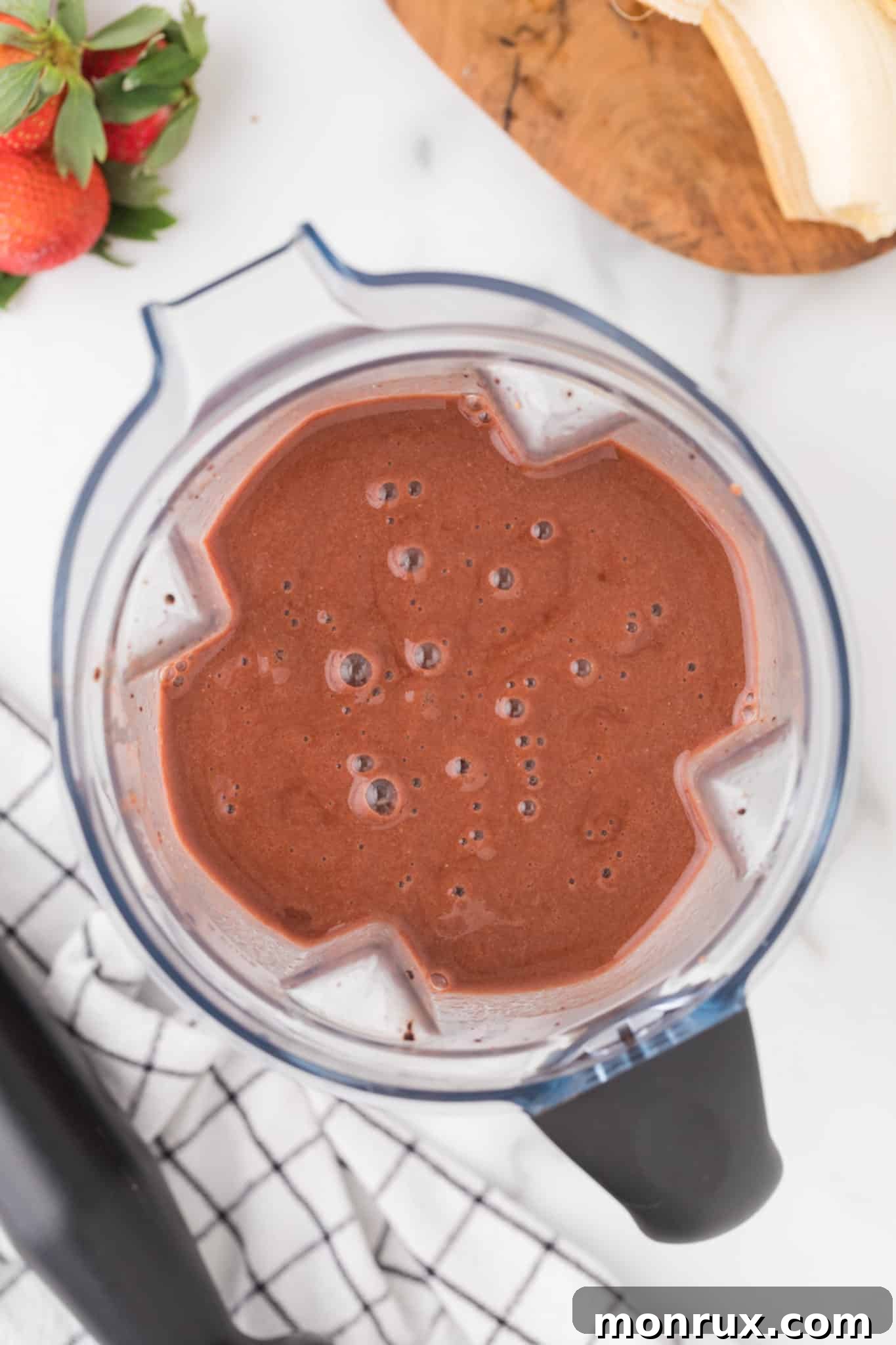 Smoothie blending in a high-speed Vitamix blender, showing the creamy texture developing for the strawberry banana chocolate mixture.