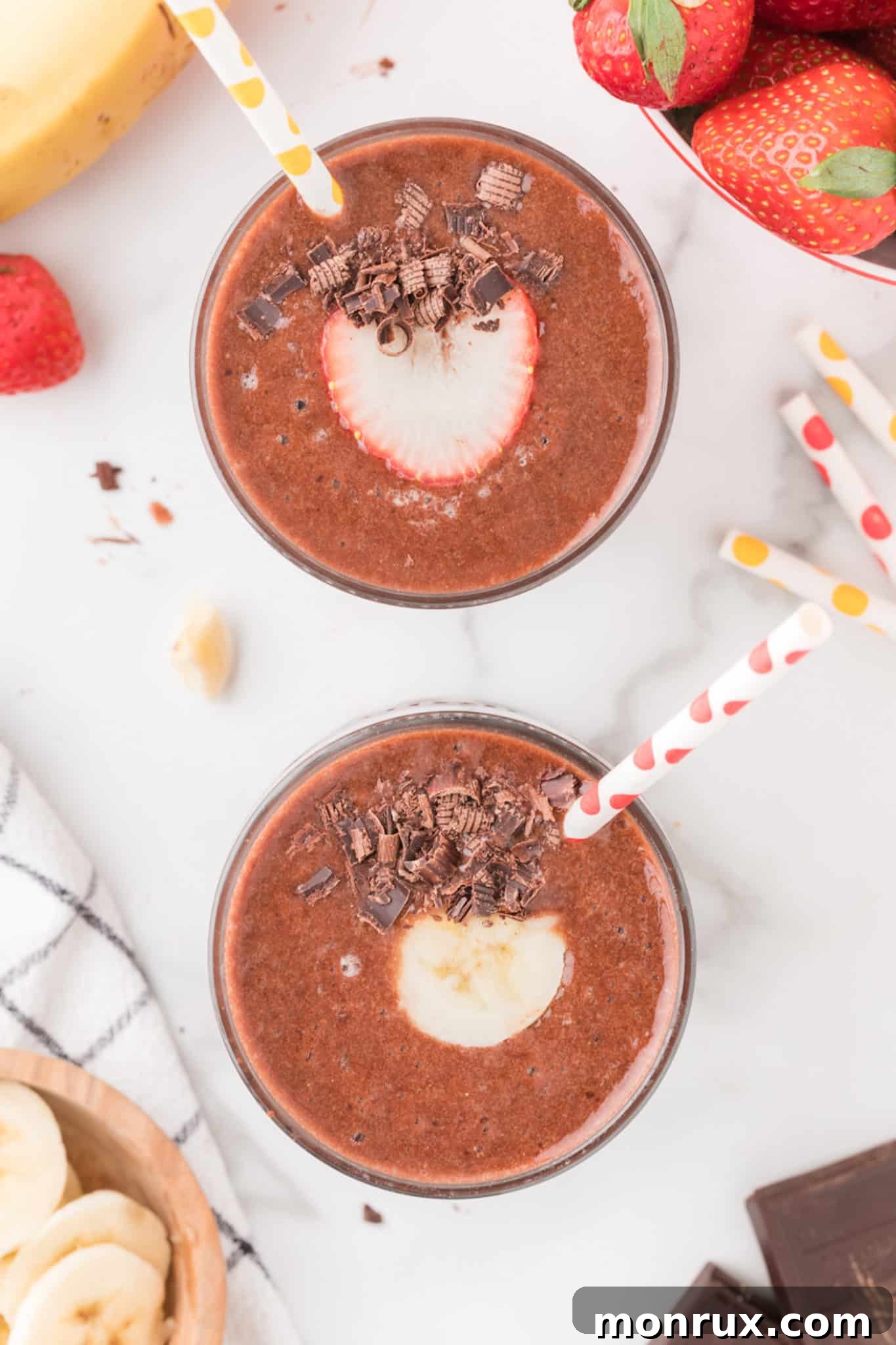 Two glasses of creamy strawberry banana chocolate smoothie, garnished with straws, ready for sharing and enjoyment.