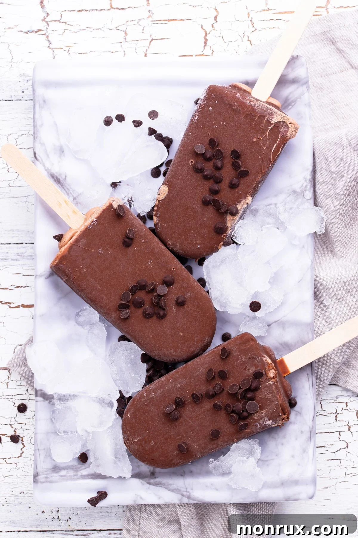 Creamy homemade vegan fudgesicles on a bed of ice, ready to be enjoyed.