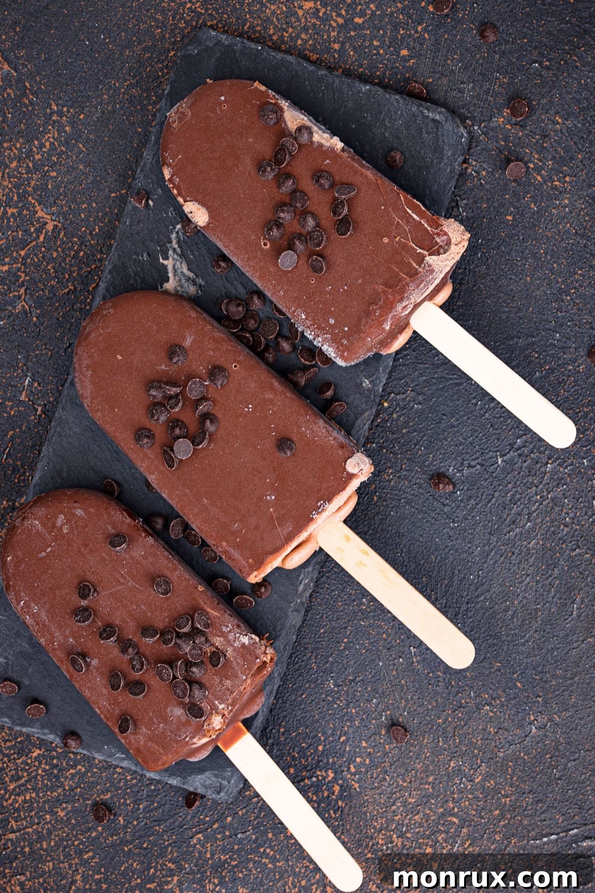 Three perfectly frozen vegan fudgesicles arranged on a serving tray, glistening and ready to be enjoyed.