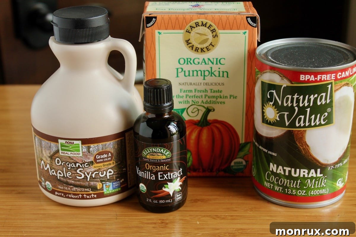 Ingredients for homemade vegan pumpkin ice cream, including coconut milk, pumpkin puree, maple syrup, vanilla extract, and pumpkin pie spice.