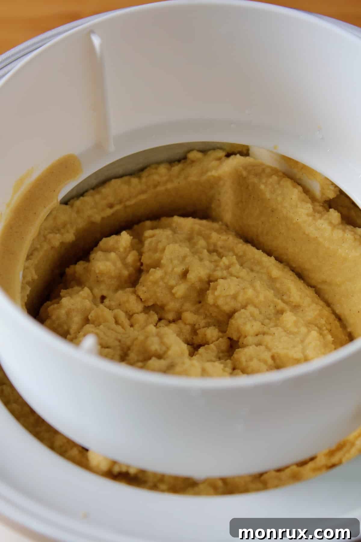Creamy vegan pumpkin ice cream churning inside an ice cream maker.