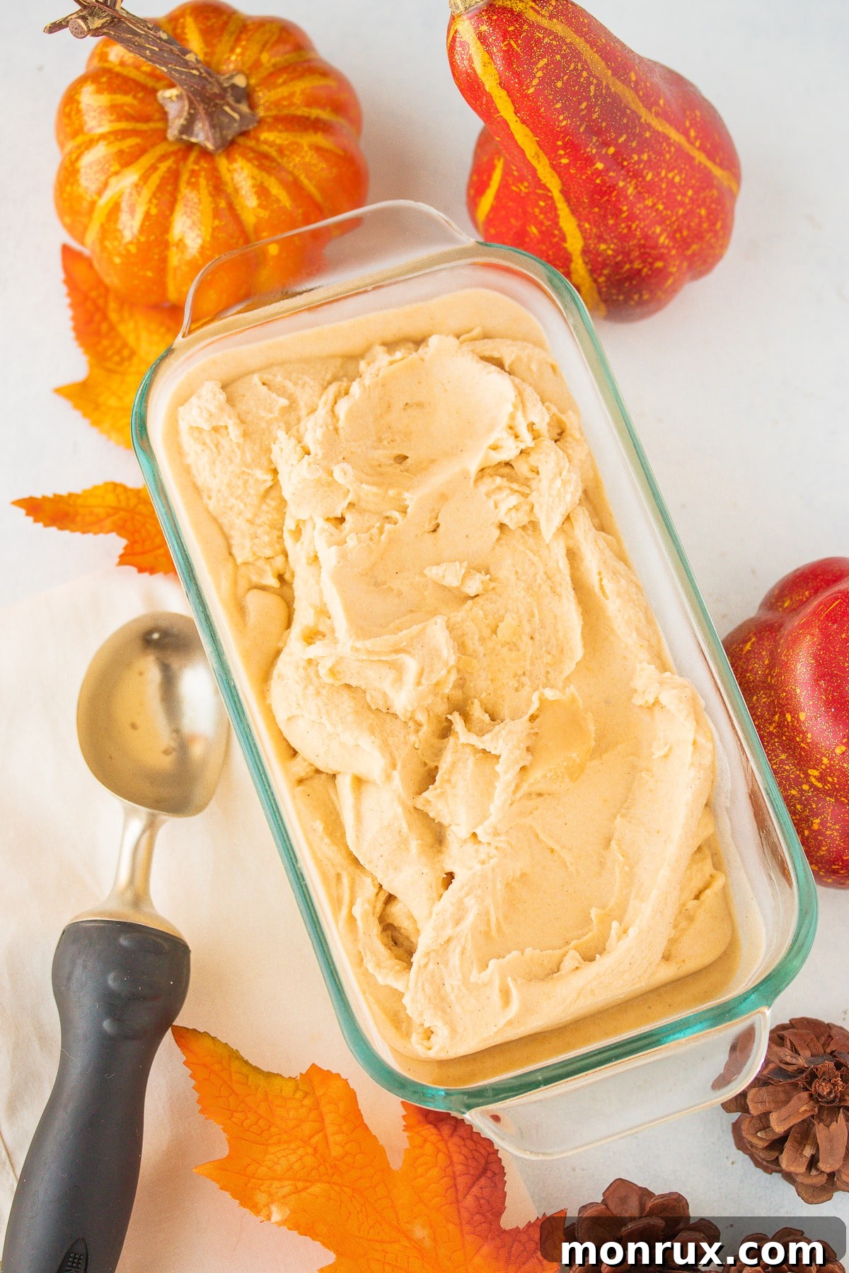 Scoops of vegan pumpkin ice cream ready to be served from a container.