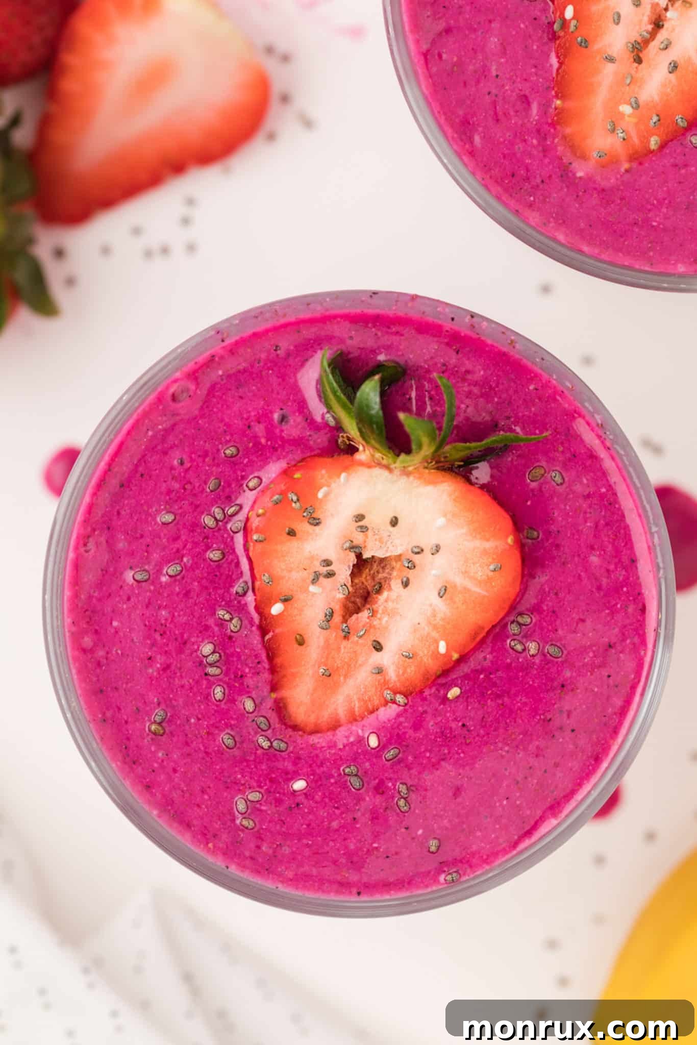 bright pink acai smoothie served in glasses with sliced strawberries