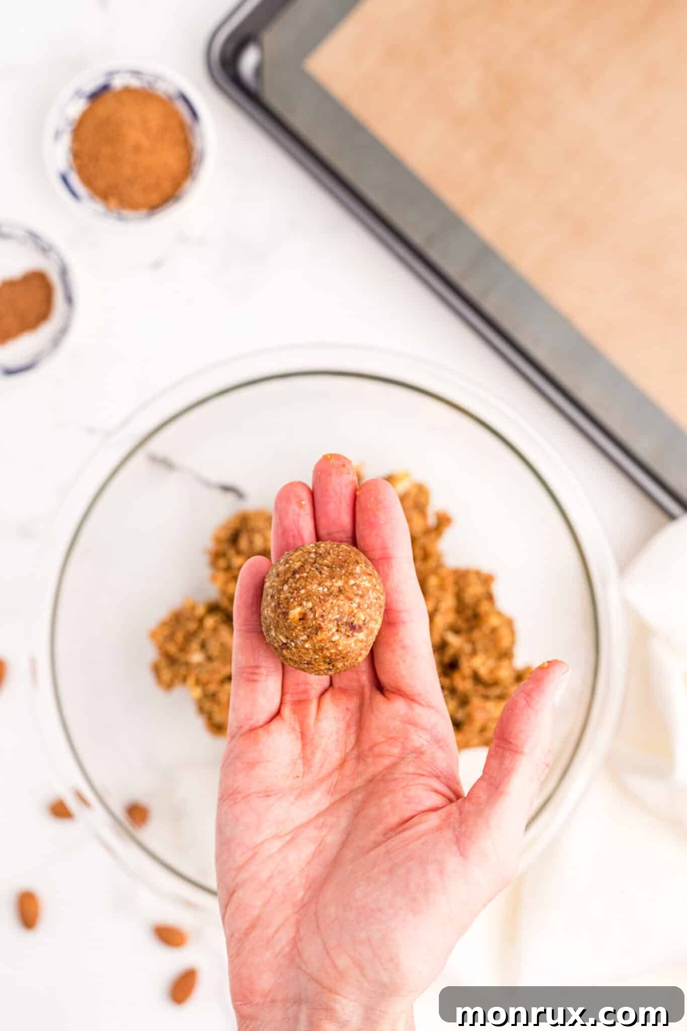 Hand holding a freshly rolled pumpkin protein ball, showcasing its perfect spherical shape.