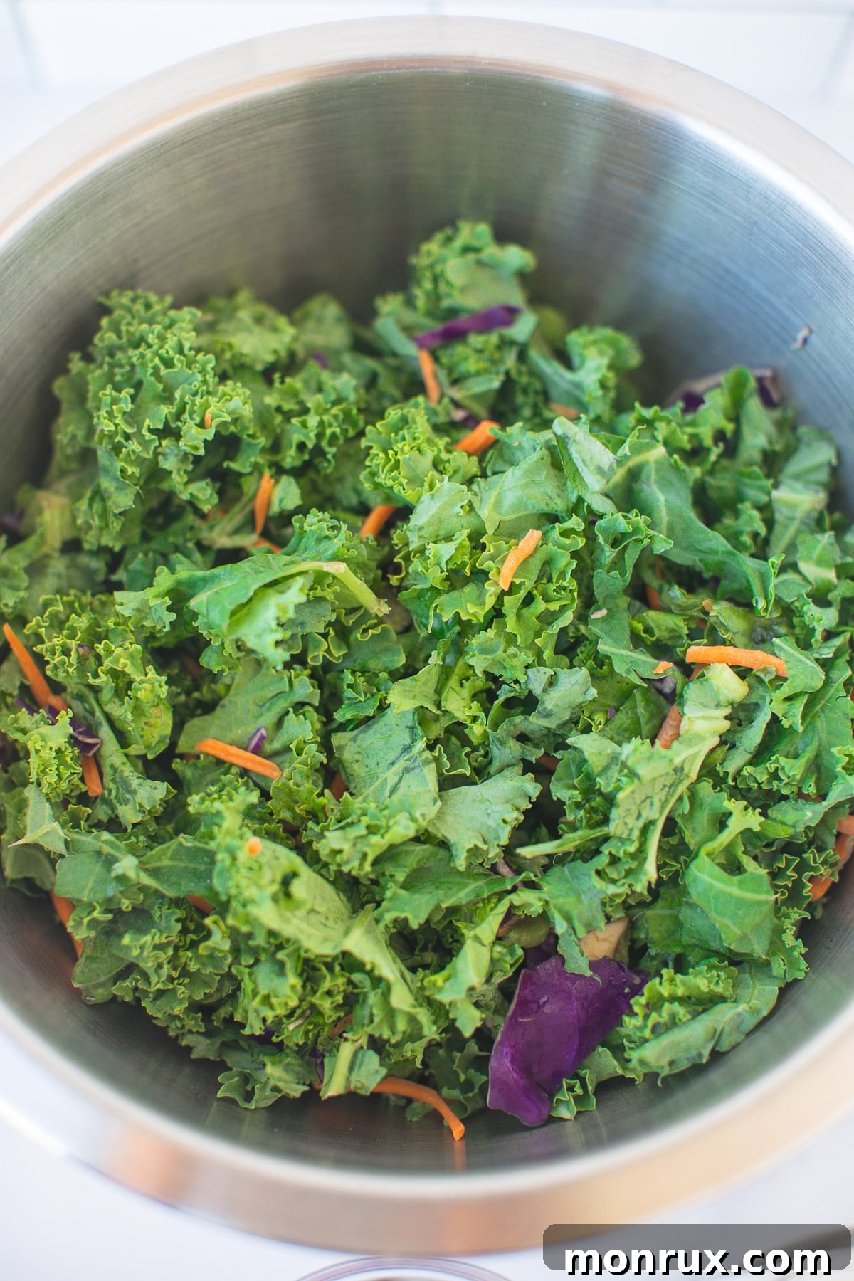A large mixing bowl filled with freshly shredded kale leaves, ready for dressing.