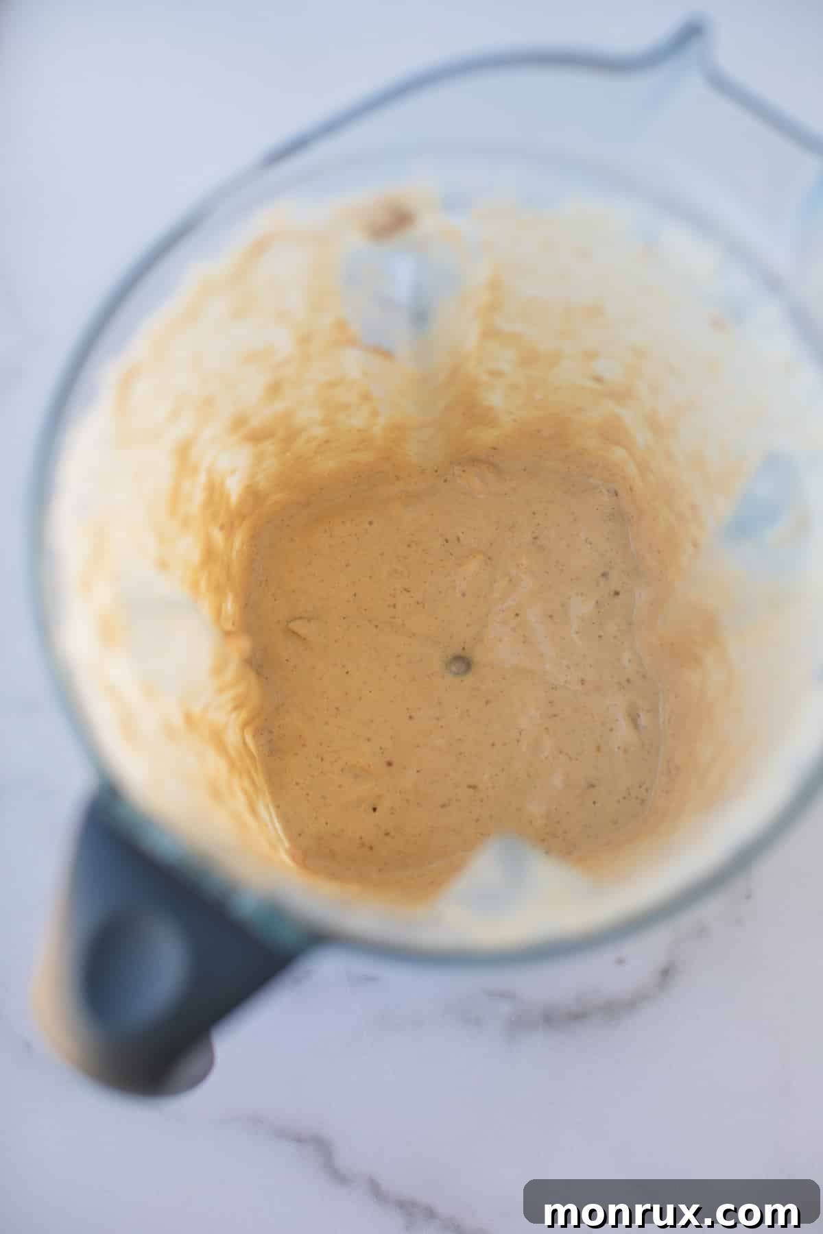 The smooth, creamy kale salad dressing fully blended in a Vitamix blender, ready to be poured.