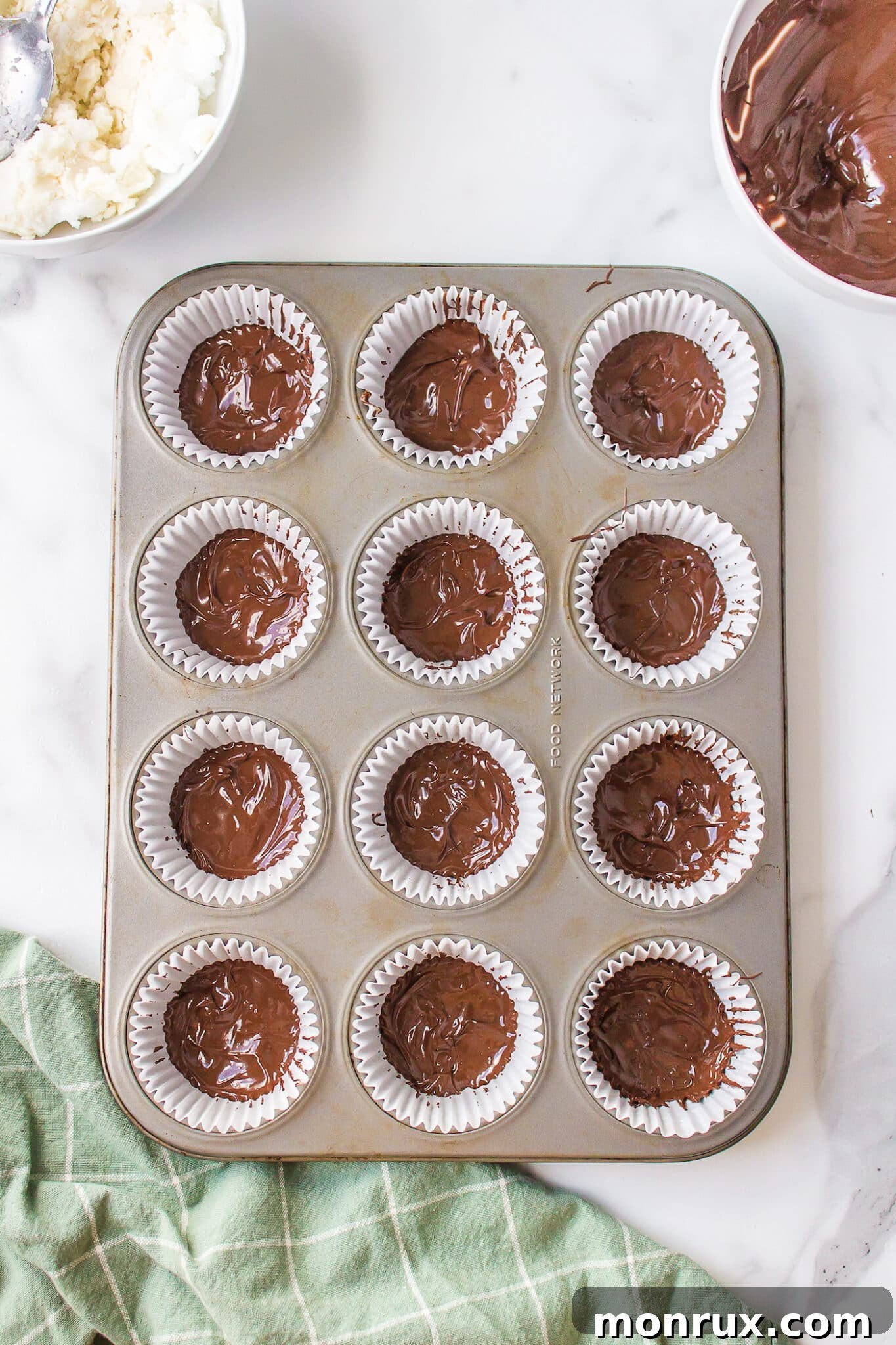 Melted chocolate neatly layered into muffin tin liners, setting the stage for homemade peppermint patties.