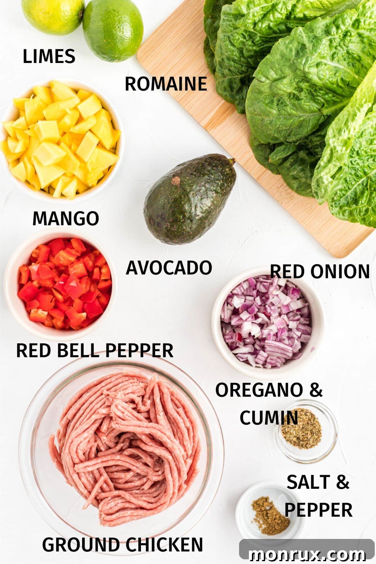 Ingredients for ground chicken lettuce tacos with labels, including mango, red bell pepper, onion, avocado, lime, and ground chicken, arranged on a cutting board.