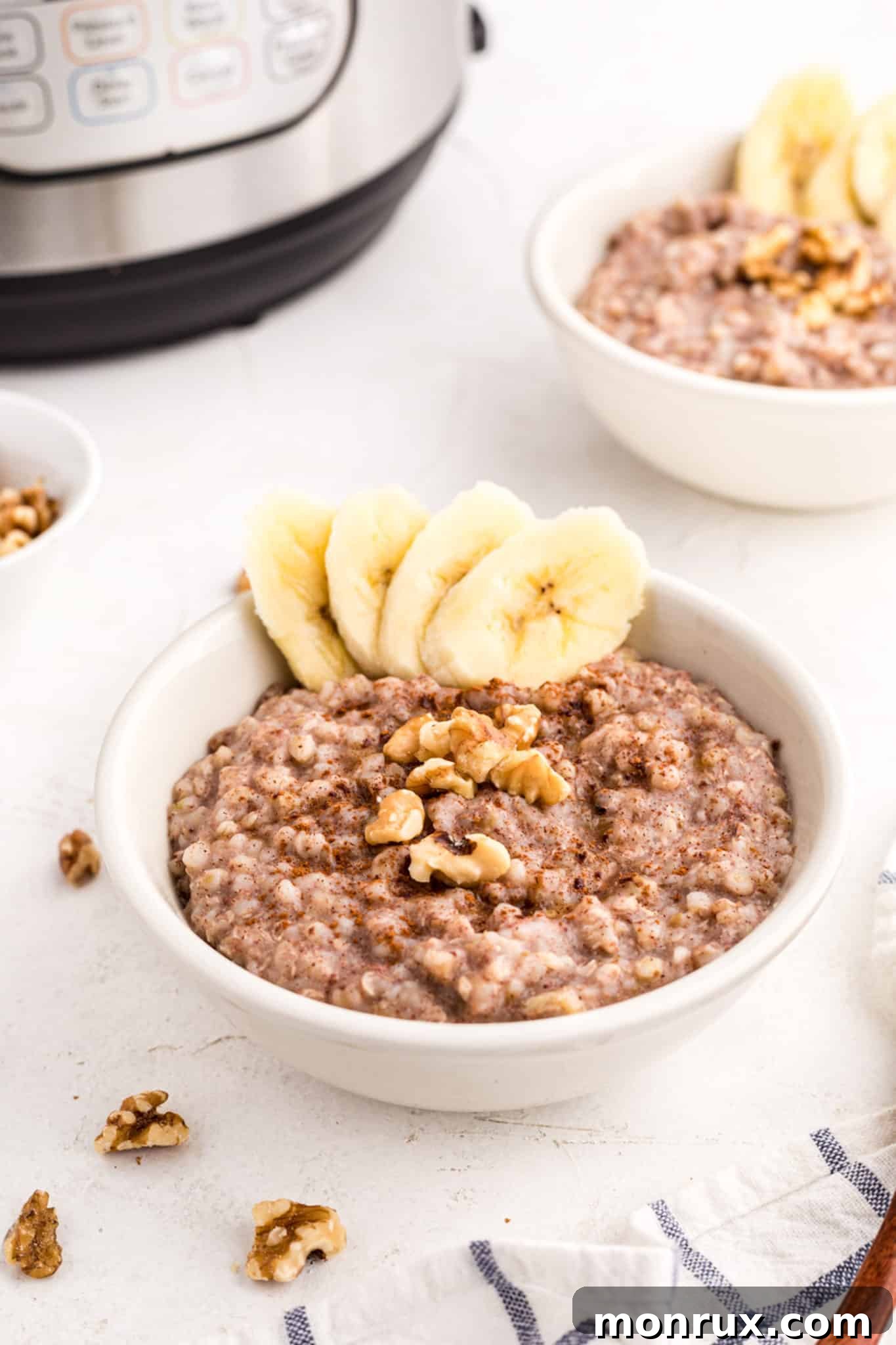 Two small bowls of buckwheat porridge topped with bananas and walnuts, ready to be served.