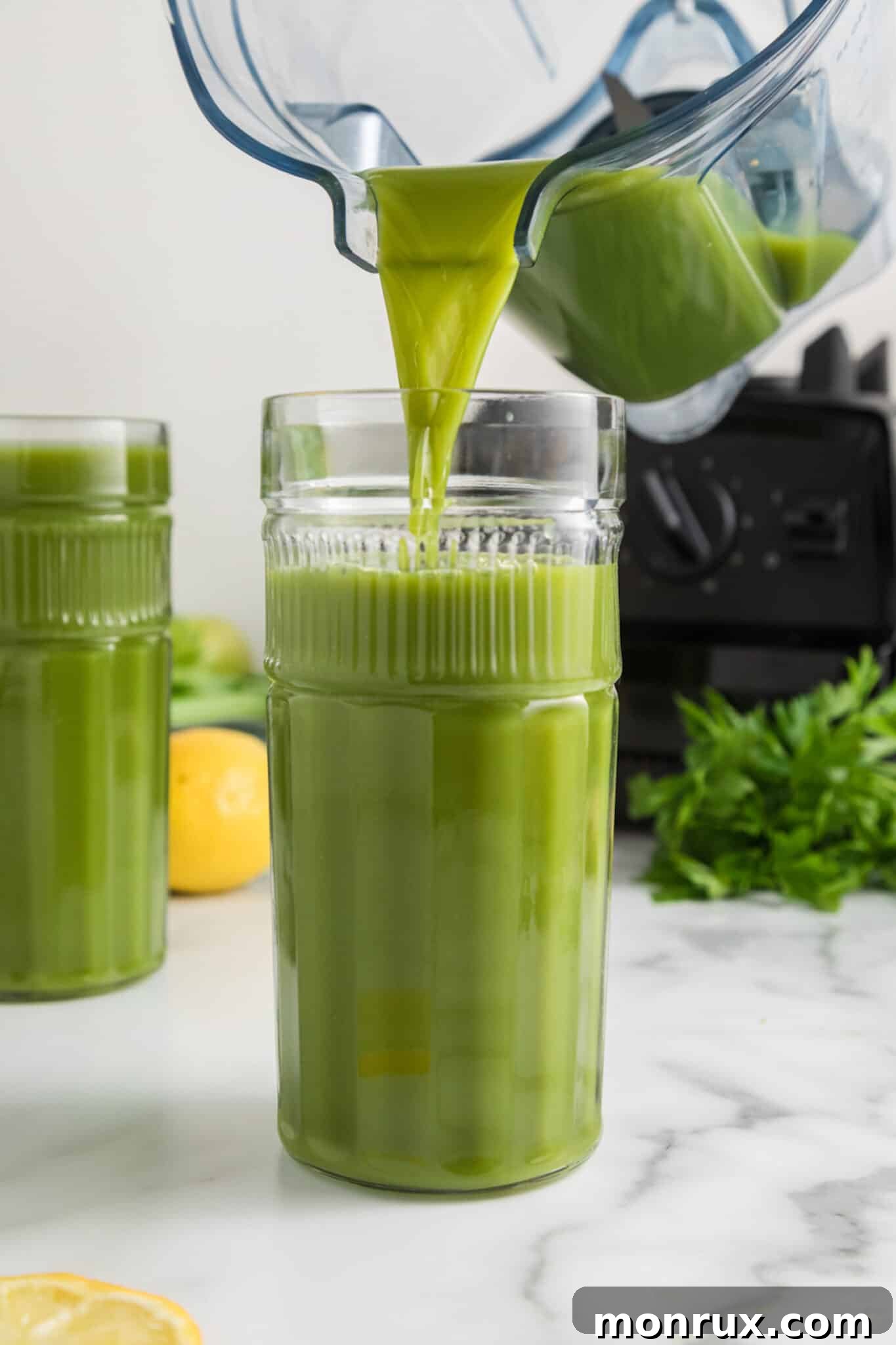 A vibrant green juice being poured from a blender into a tall glass, ready to be served.