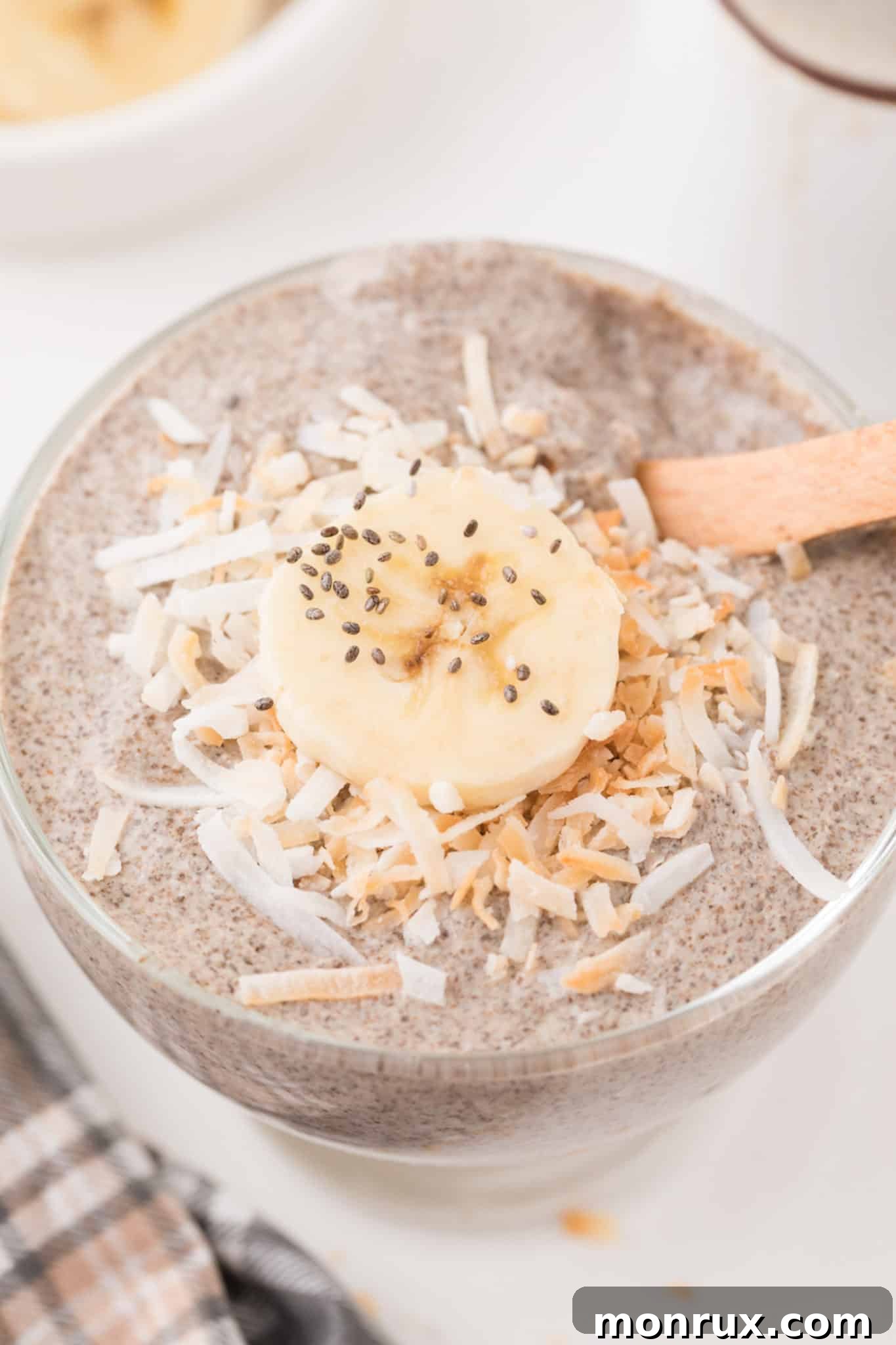 A close-up shot of the finished Whole30 Chia Pudding, beautifully garnished with toasted coconut flakes and fresh banana slices, ready to be served.