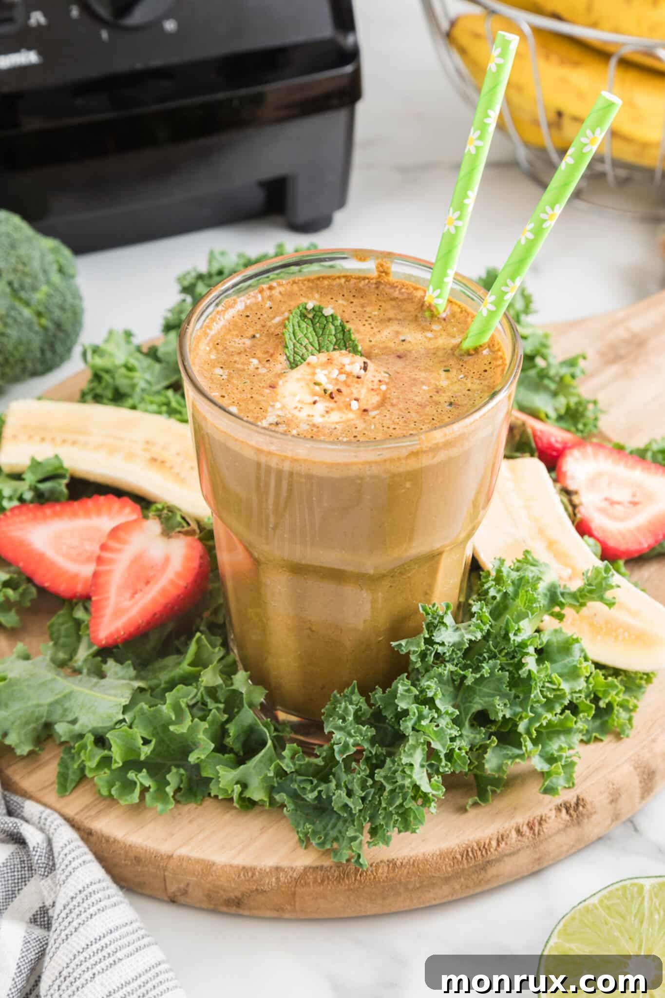 Cocoa green smoothie in a glass with two green straws, highlighting its rich, healthy appeal.