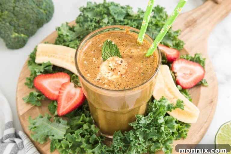 Cocoa green smoothie in a glass with two green straws, showcasing its vibrant appeal.