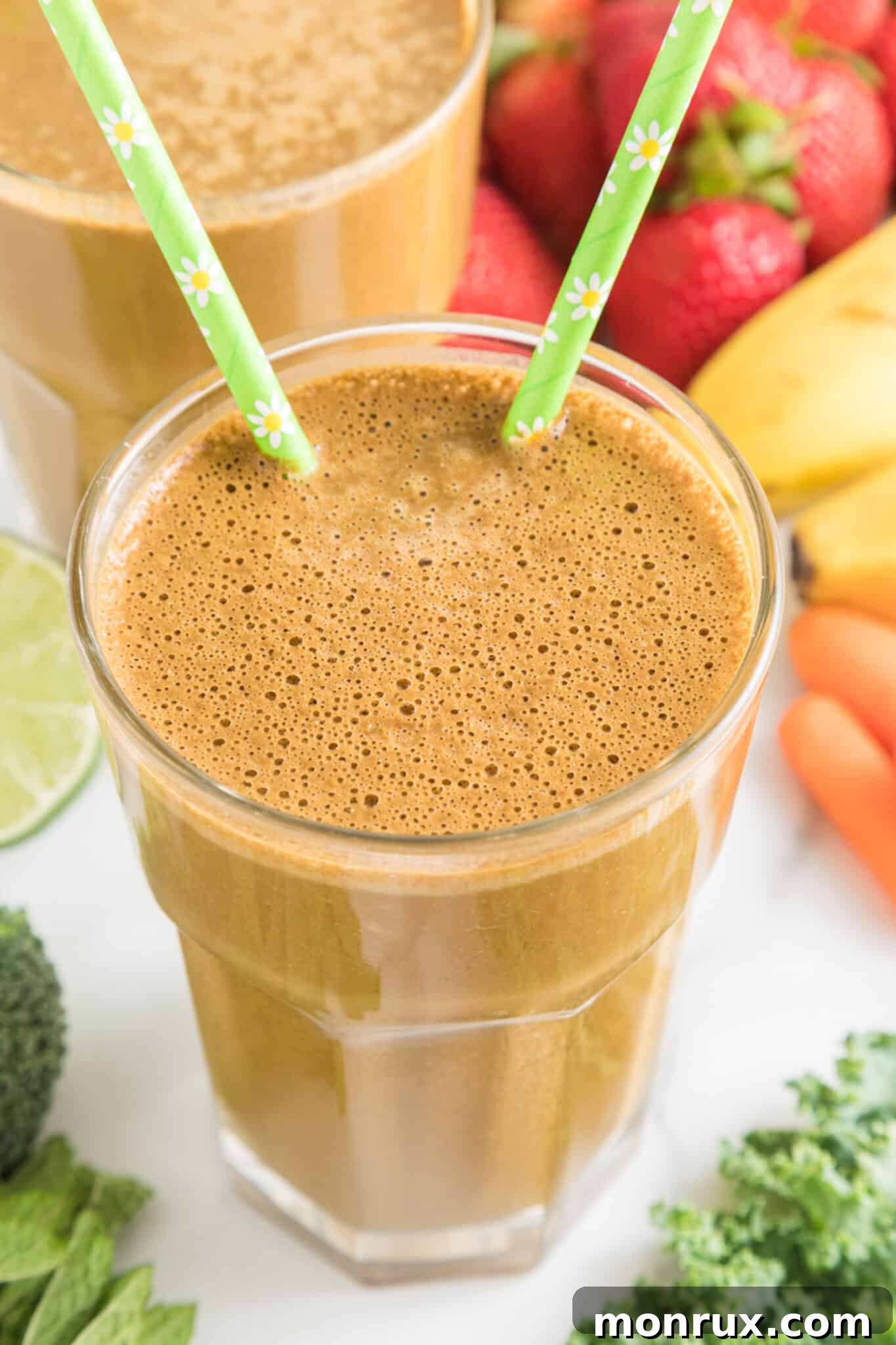A close-up of the finished cocoa green smoothie, served in a glass with two green straws, emphasizing its tempting texture.