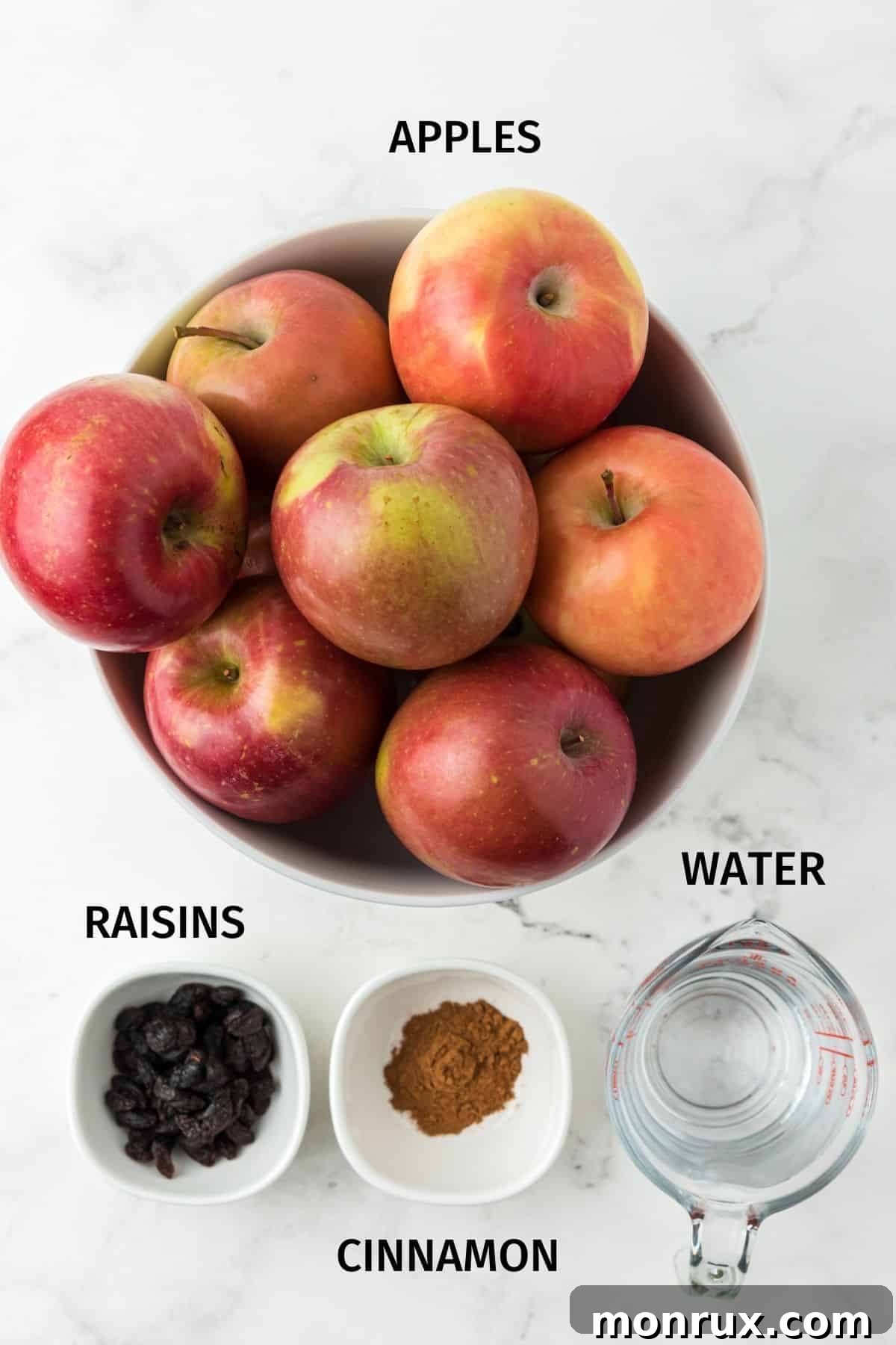 Fresh apples and a cinnamon stick, key ingredients for crockpot applesauce, arranged on a tabletop.