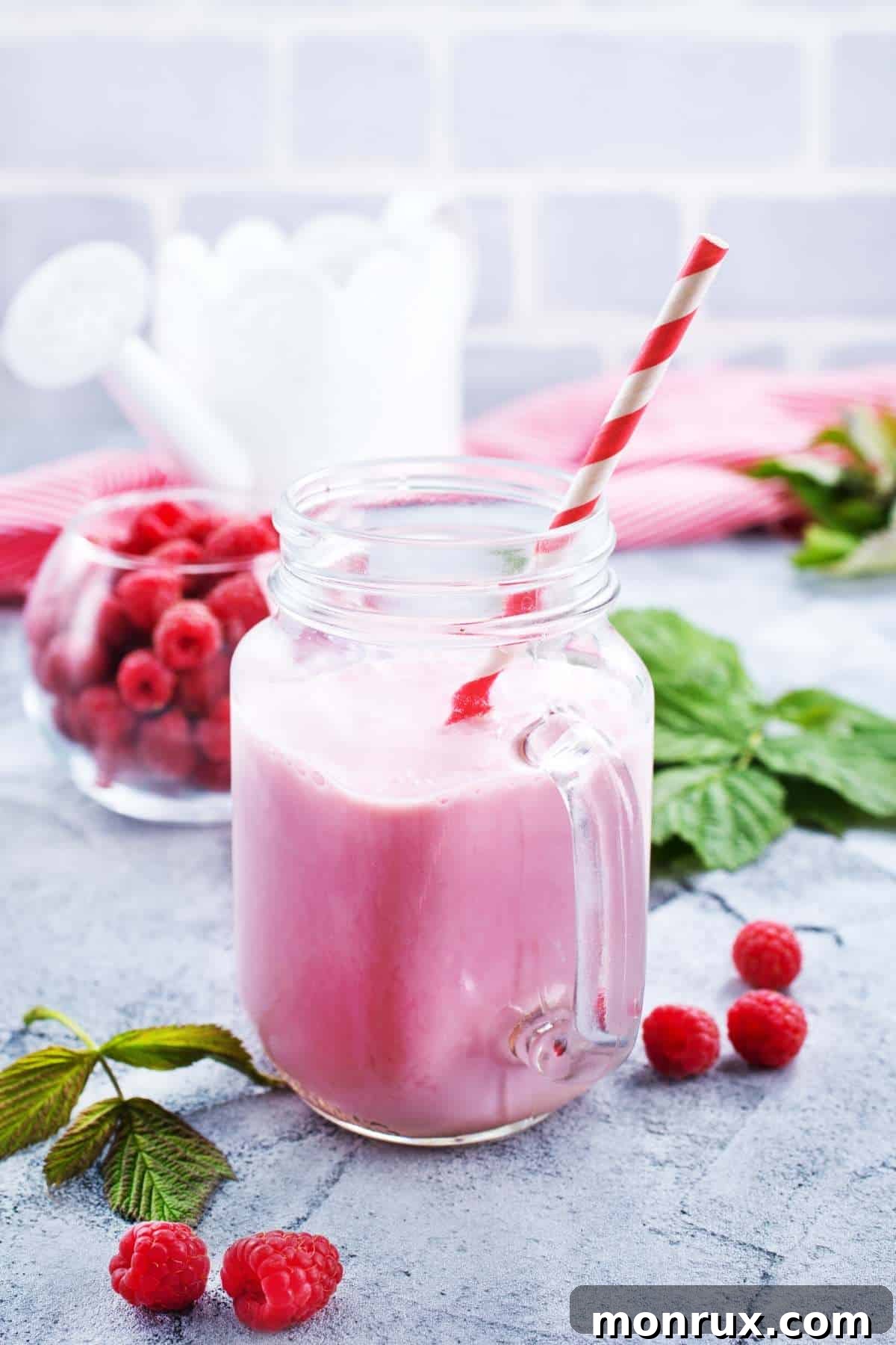 Vibrant raspberry smoothie in a glass with a striped straw, ready to be enjoyed.