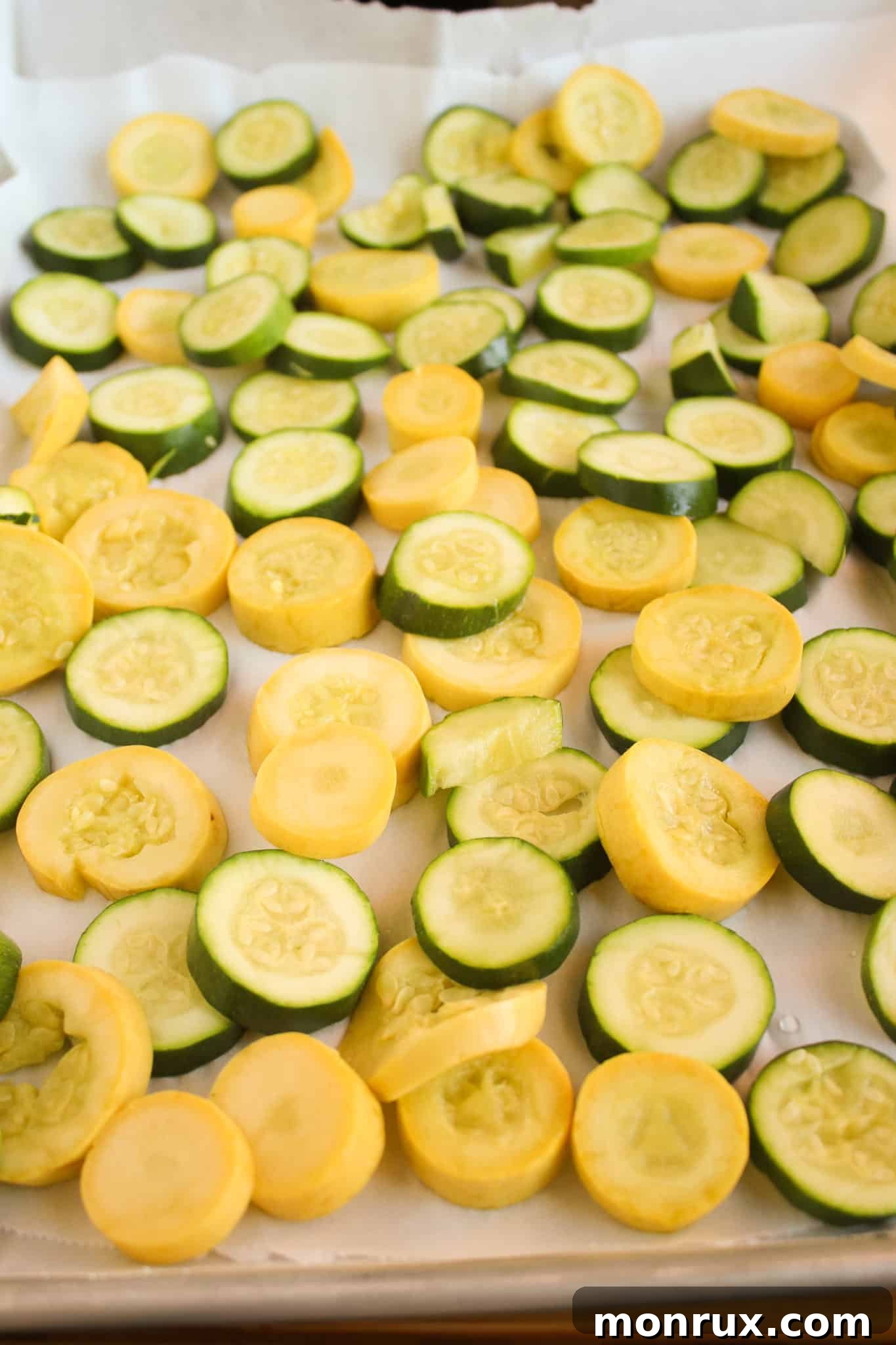 Frozen yellow squash chunks on a parchment-lined baking sheet, ready for storage.