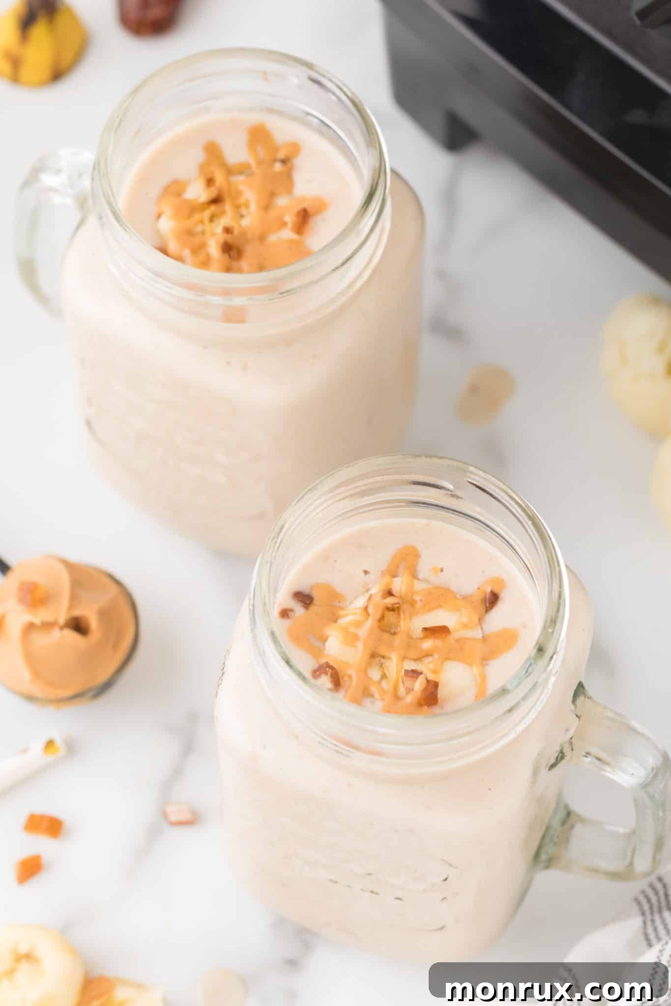 Two glasses of creamy peanut butter cauliflower smoothie, garnished lightly with chopped nuts.