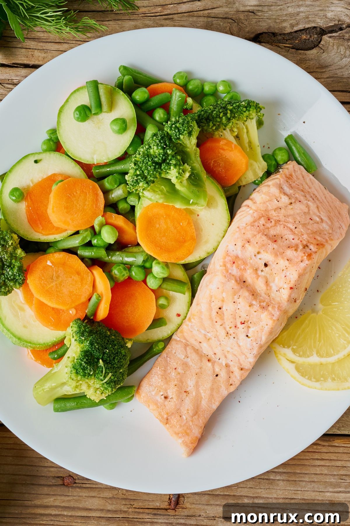 steamed vegetables with salmon served on white plate.