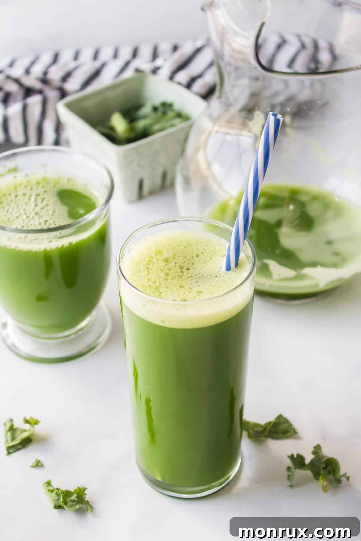 A refreshing glass of green detox juice with a straw, garnished with a slice of lime, sitting on a natural wood surface.