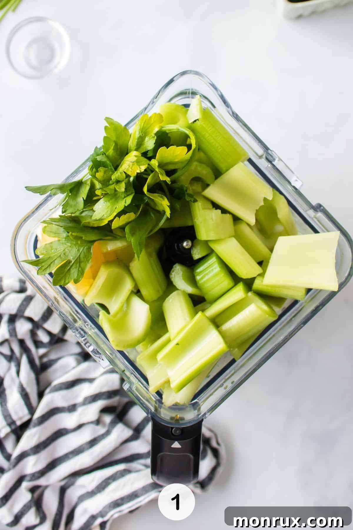Freshly washed and cut ingredients for detox green juice are placed inside a blender pitcher, ready for blending.