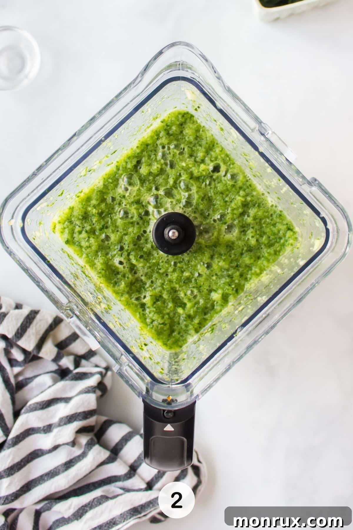 Vibrant green juice is being blended smoothly in a high-speed blender, creating a rich, liquid consistency.