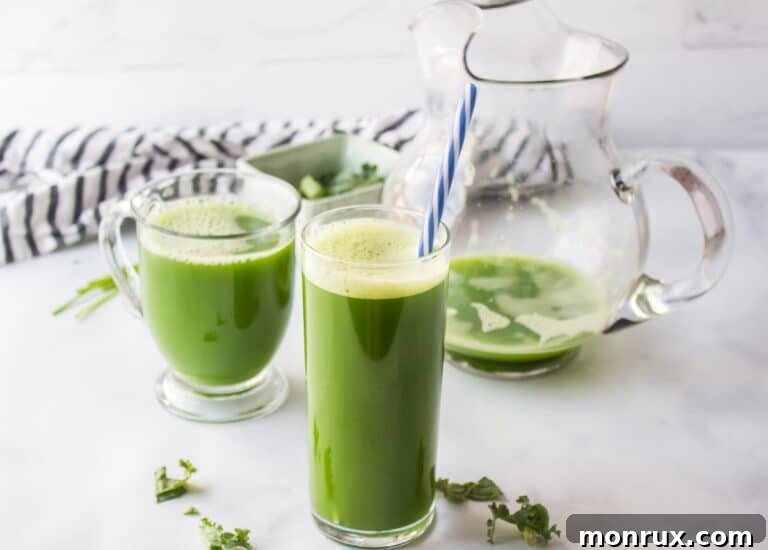 A glass of freshly made green juice sits on a clean, light-colored table, invitingly ready to drink.